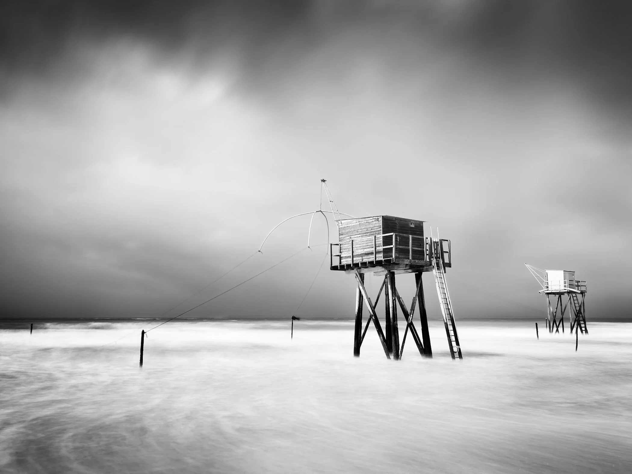 Fishing Hut on Stilts Study 4, a minimalist black-and-white long-exposure seascape of traditional fishing huts on the French coast by Gerald Berghammer.
