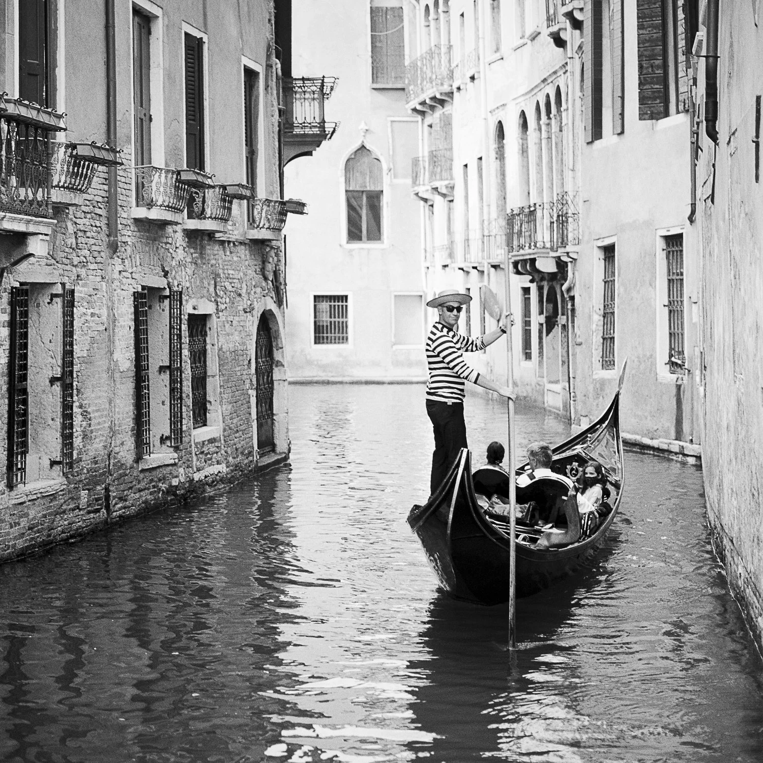 Close-up of Gondoliere Study 1 by Gerald Berghammer, showing a gondolier and passengers between the historic façades of Venice.