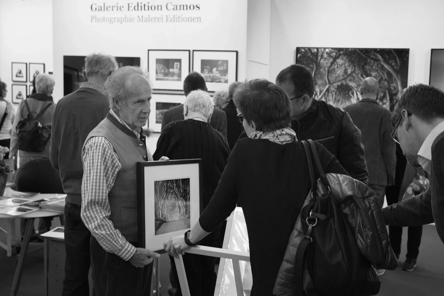 Visitors examining a framed black-and-white photograph by Gerald Berghammer at the Galerie Edition Camos stand, art KARLSRUHE 2017.