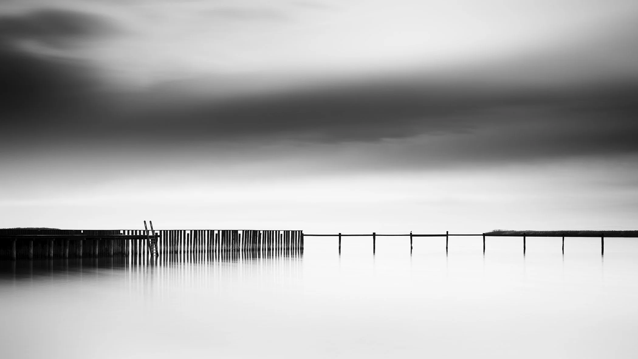 Black and white panorama of a swimming area with dock and pier under a cloudy sky, Austria
