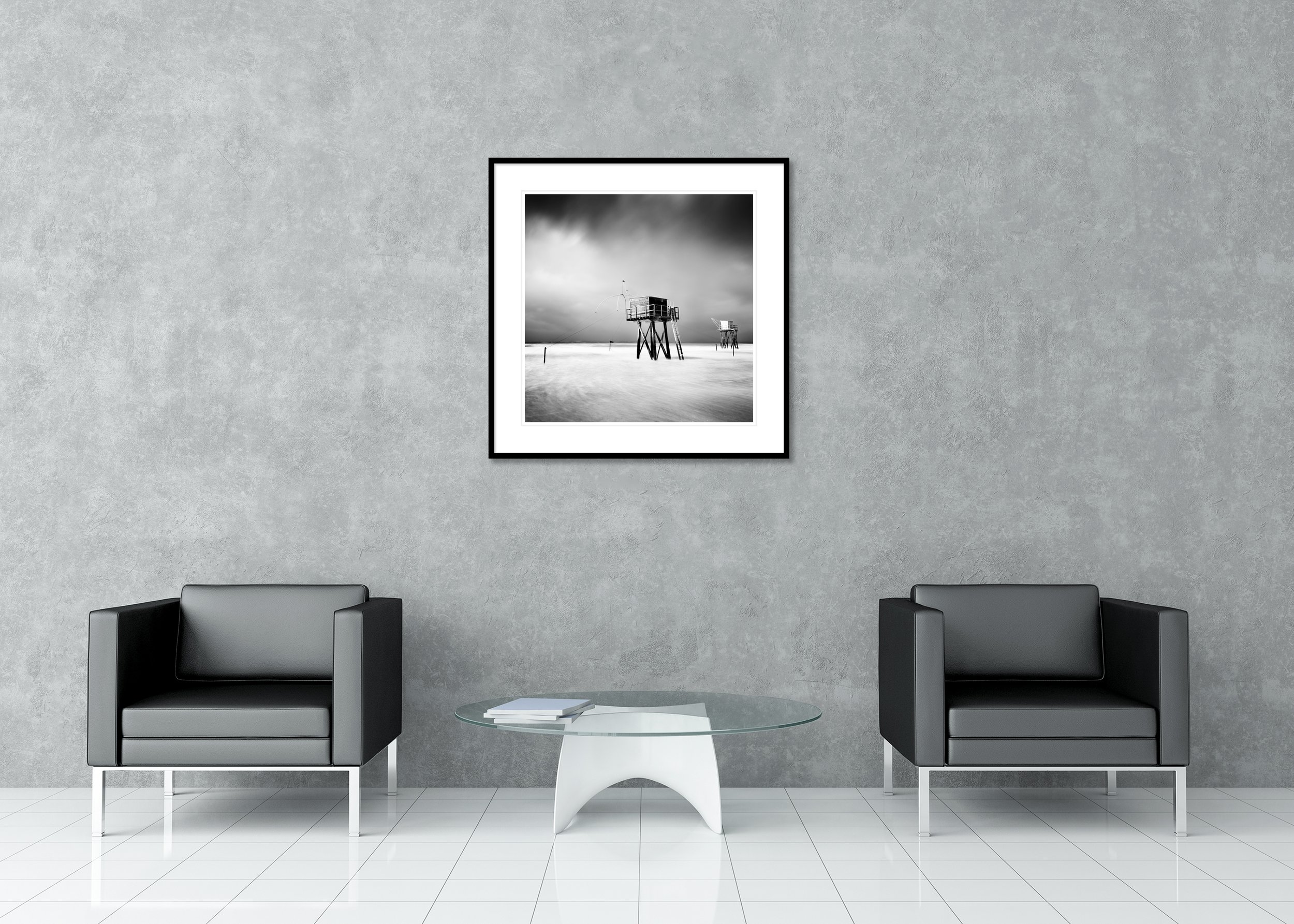 Black and white long-exposure photo of fishing huts on stilts at sea, dramatic sky and minimalist coast, archival pigment print in classic frame with passe-partout.