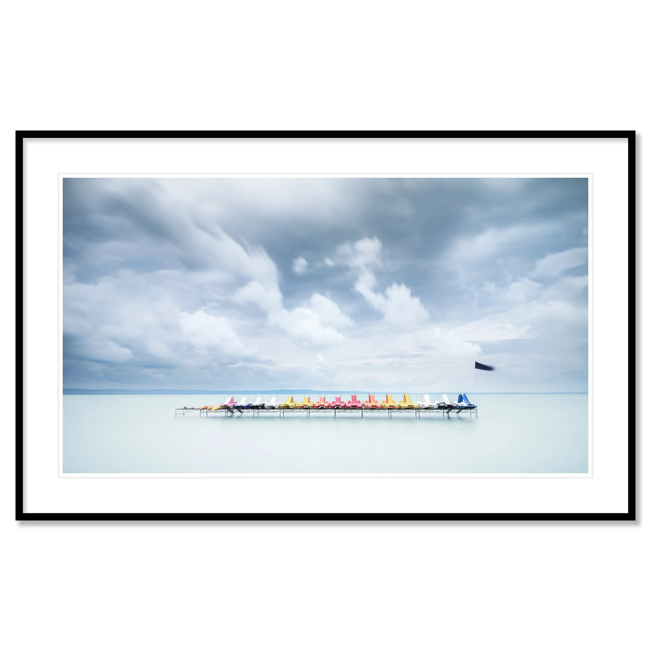 Gerald Berghammer - Color long exposure waterscape photography. Colorful paddle boats lined up on a dock over calm water, under a cloudy sky. Classic framed black