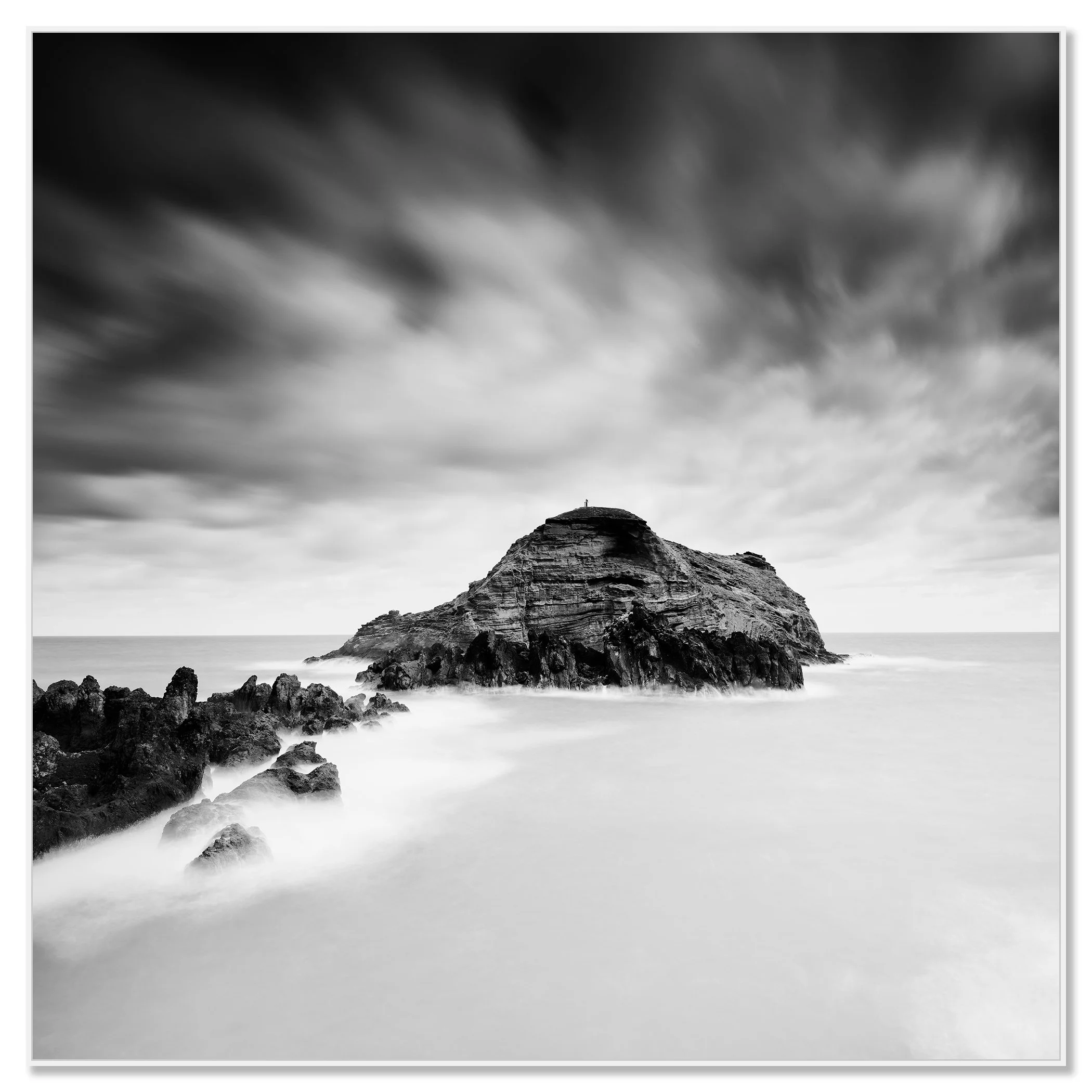 Black-and-white photograph of a rocky island in calm water beneath a cloudy sky – framed ArtBox white