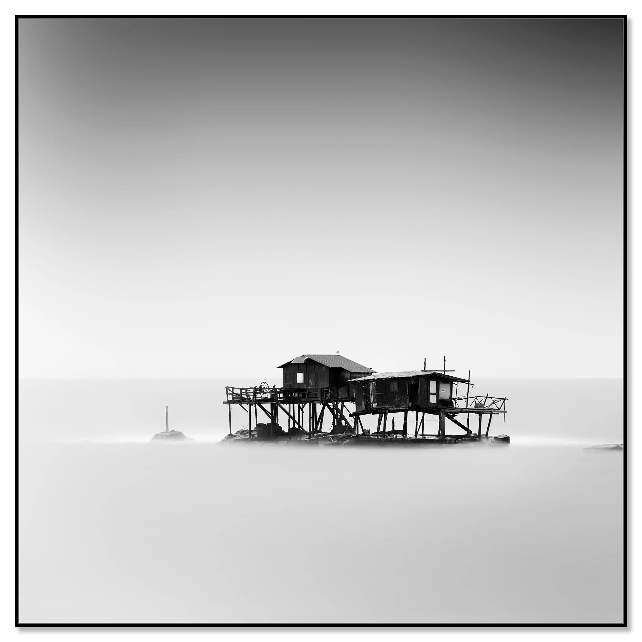Monochrome fine art photograph of fishing huts on stilts in the sea off Marina di Pisa, Tuscany – framed ArtBox black