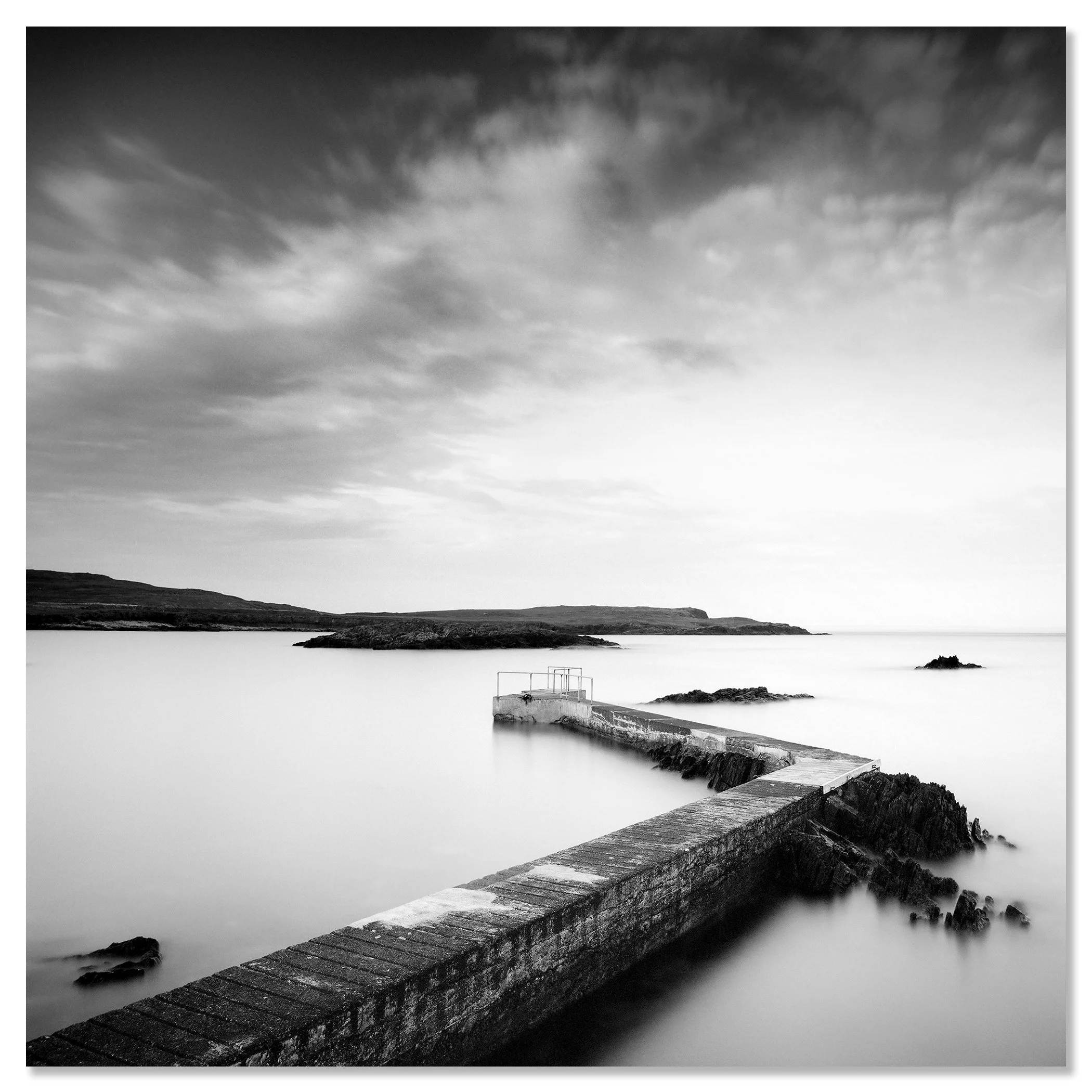 © 2014 Gerald Berghammer - Black and white seascape photography. A Concrete pier extends into calm seawater with rocky edges, under a cloudy sky. Chromaluxe frameless