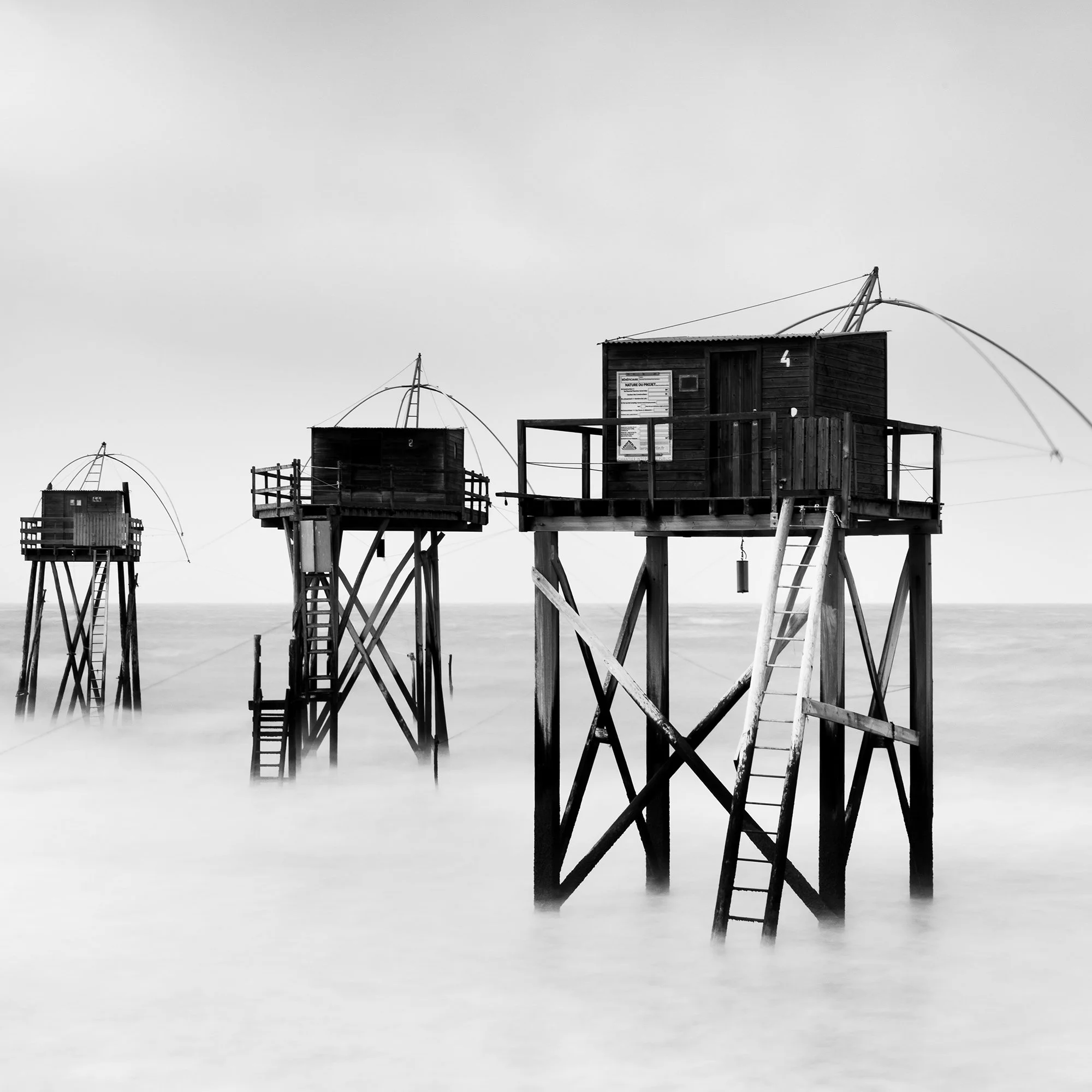 Monochrome long-exposure seascape with wooden fishing huts on stilts and misty water, Detail 3