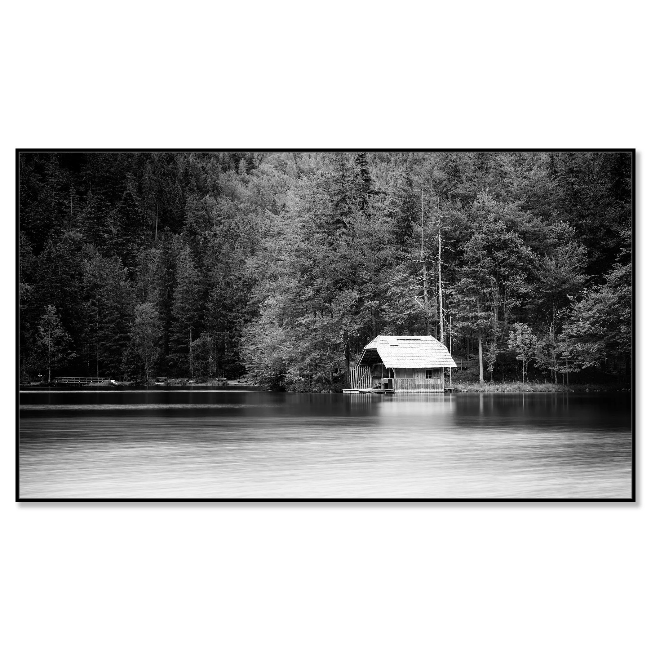 Calm lake in black and white with a small boathouse, wooden jetty and trees along the shore – framed ArtBox black