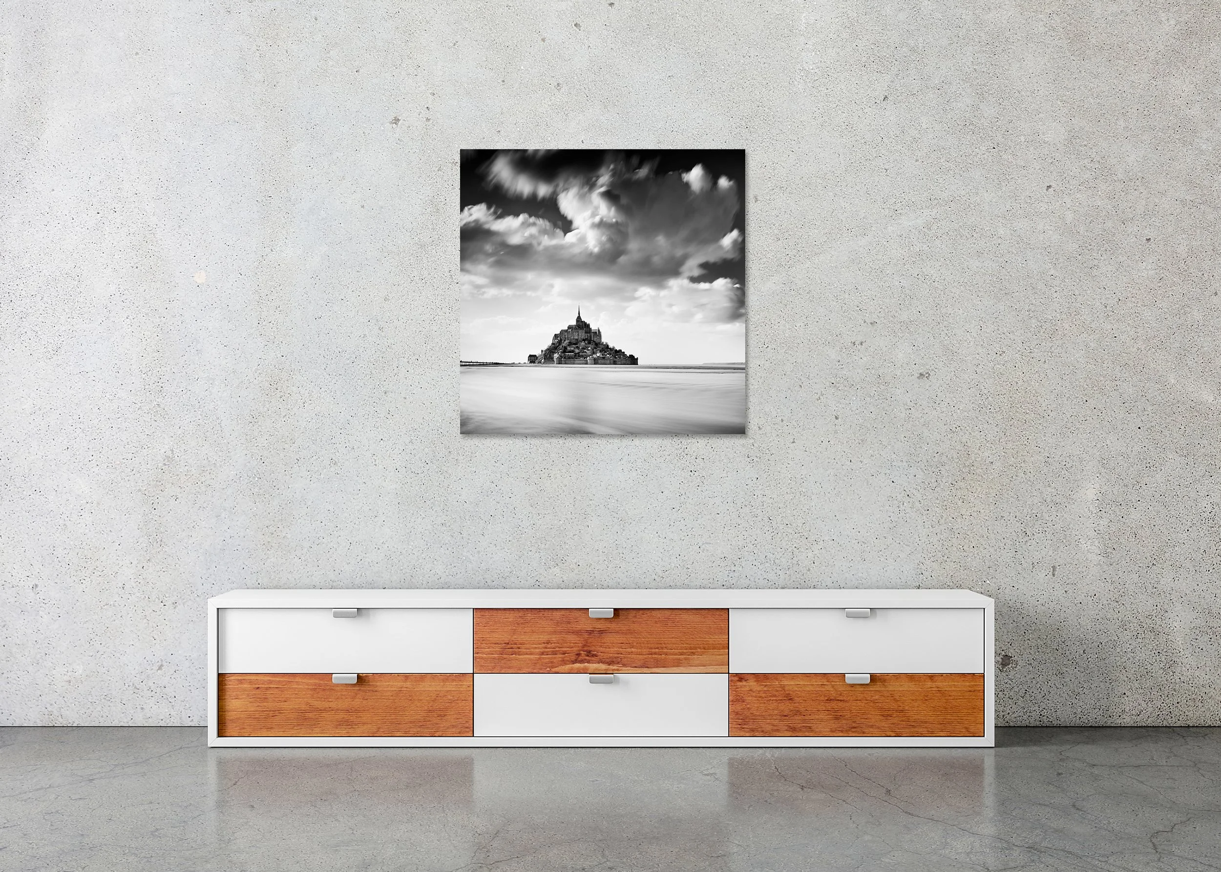 Monochrome photo print of Mont Saint-Michel in France, mounted to Dibond without a frame, above tidal water under a vast cloudy sky.