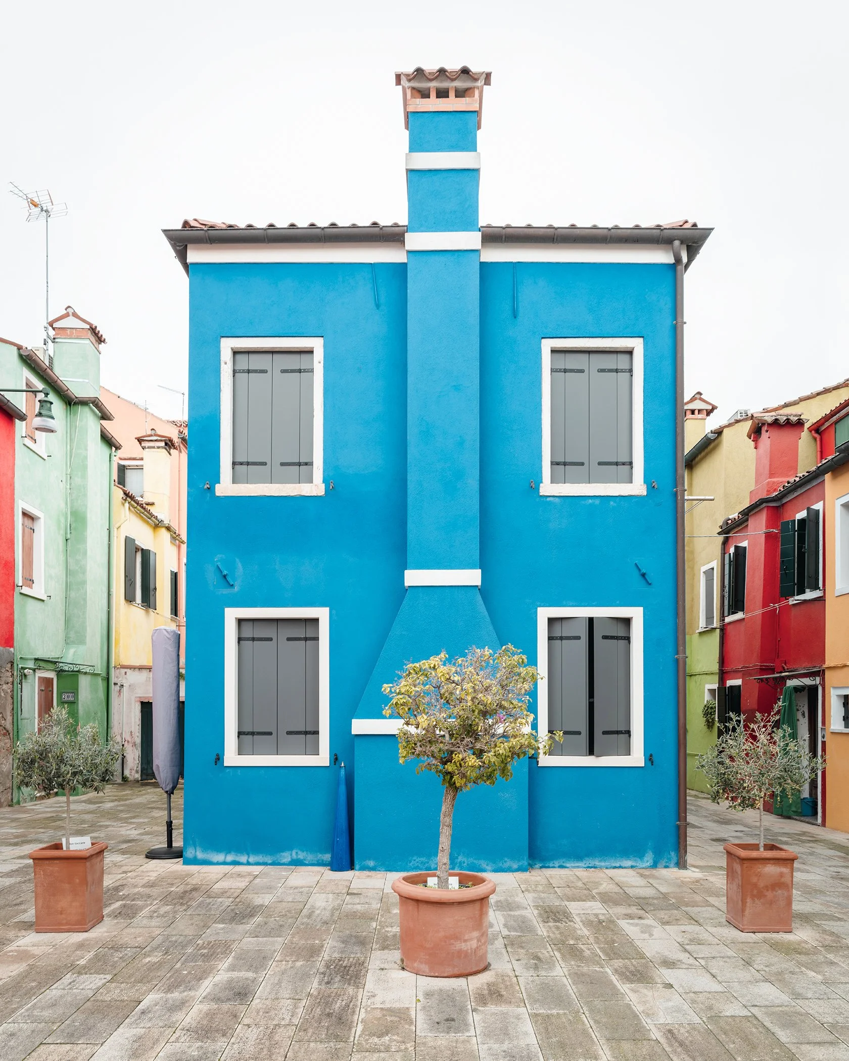 The Blue House, blue façade with grey shutters and a small tree in Burano, Venetian Lagoon, Venice, by Gerald Berghammer.