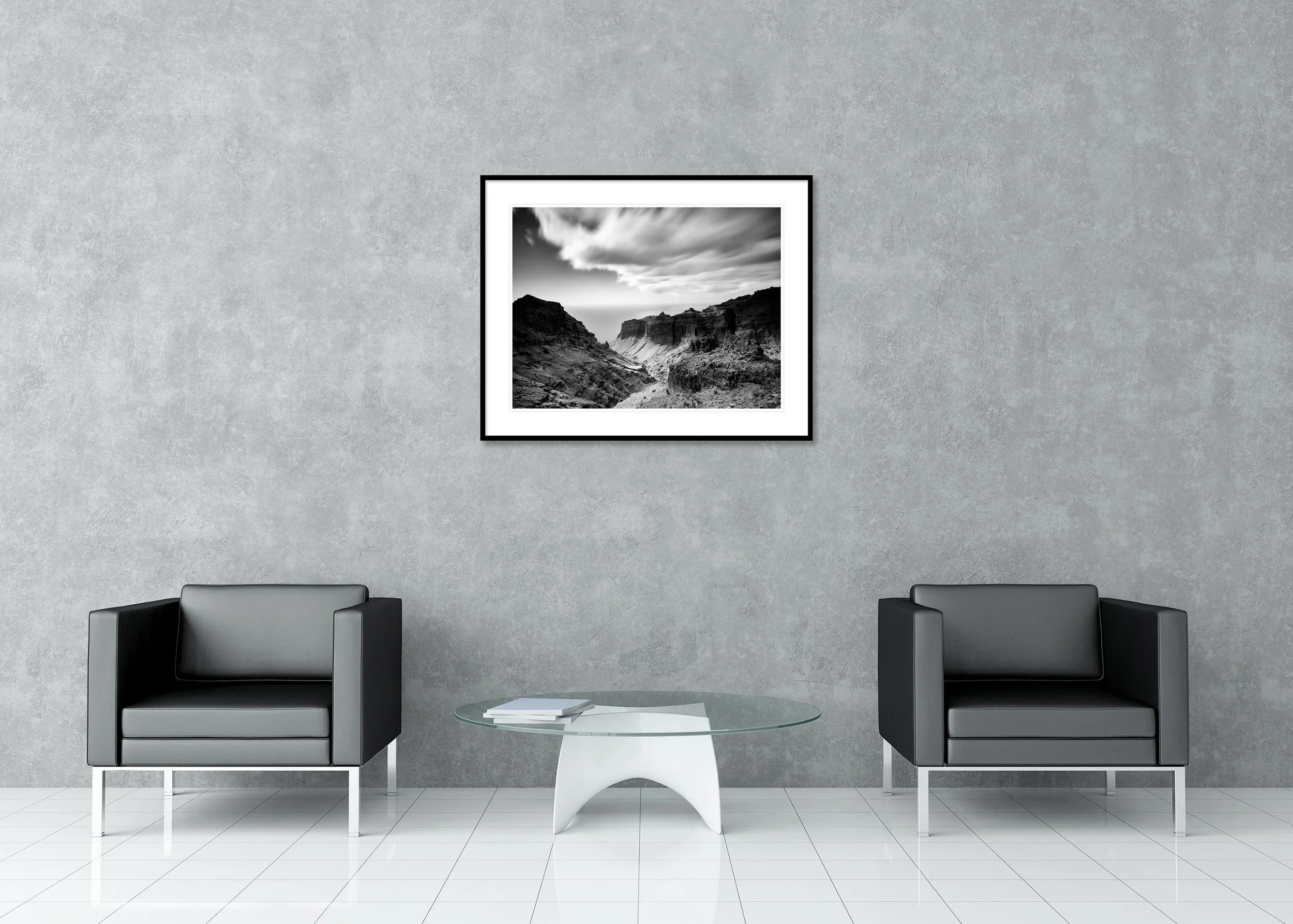 Black and white wall art showing a rugged volcanic ravine leading towards the sea, archival pigment print in a classic frame with a mount.