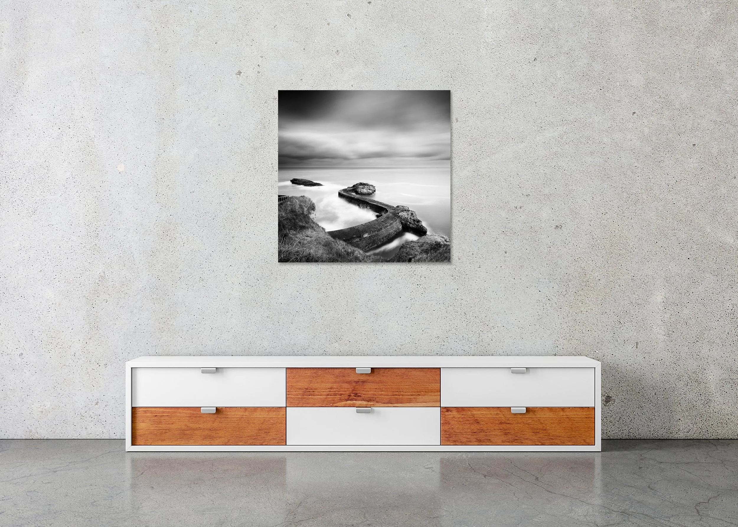 Black and white print of a curved harbour breakwater pier with rocks and smooth long-exposure sea, mounted to Dibond, frameless.