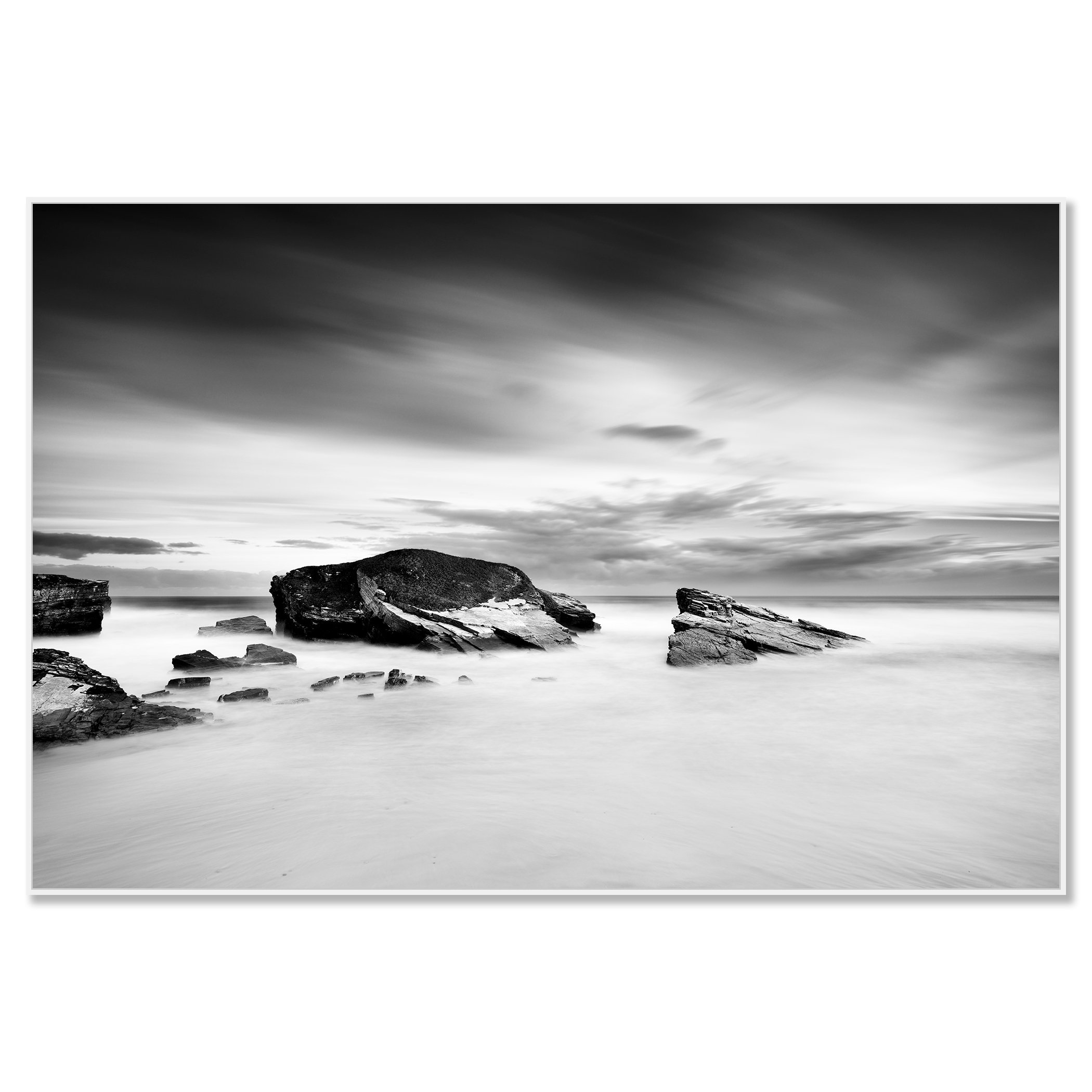 Monochrome long-exposure seascape with rocky coast and large rocks beneath overcast skies – framed ArtBox white