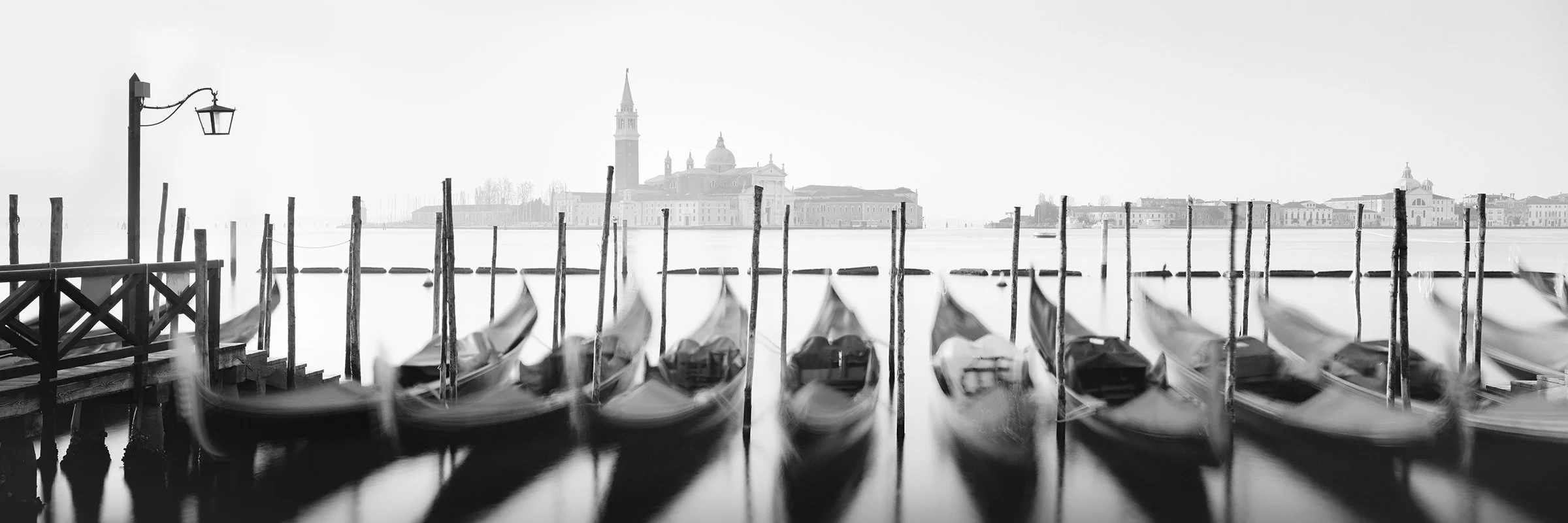 Twelve Gondolas by Gerald Berghammer, analogue black-and-white panoramic photograph of twelve Venetian gondolas and San Giorgio Maggiore, Venice, Italy.