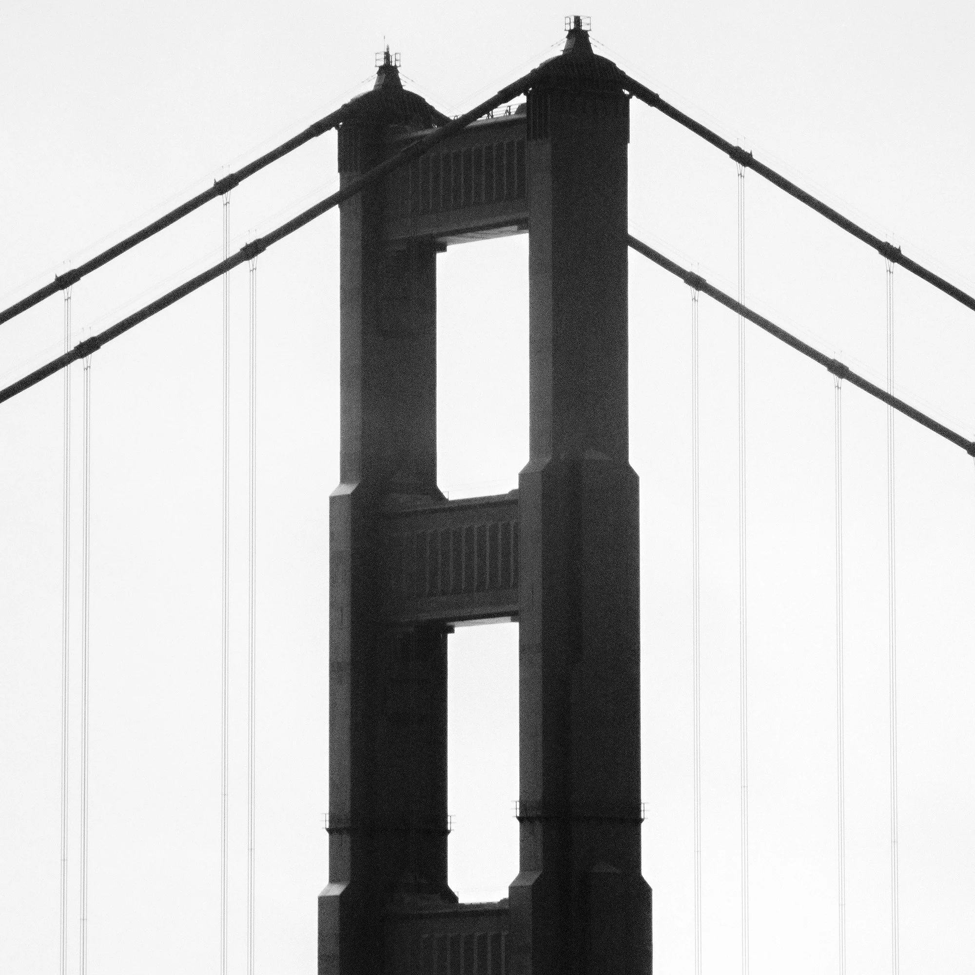 © 2015 Gerald Berghammer - Black and white photo. Golden Gate Bridge in San Francisco, seen from the side, with the city skyline faintly visible in the background. Print detail 3