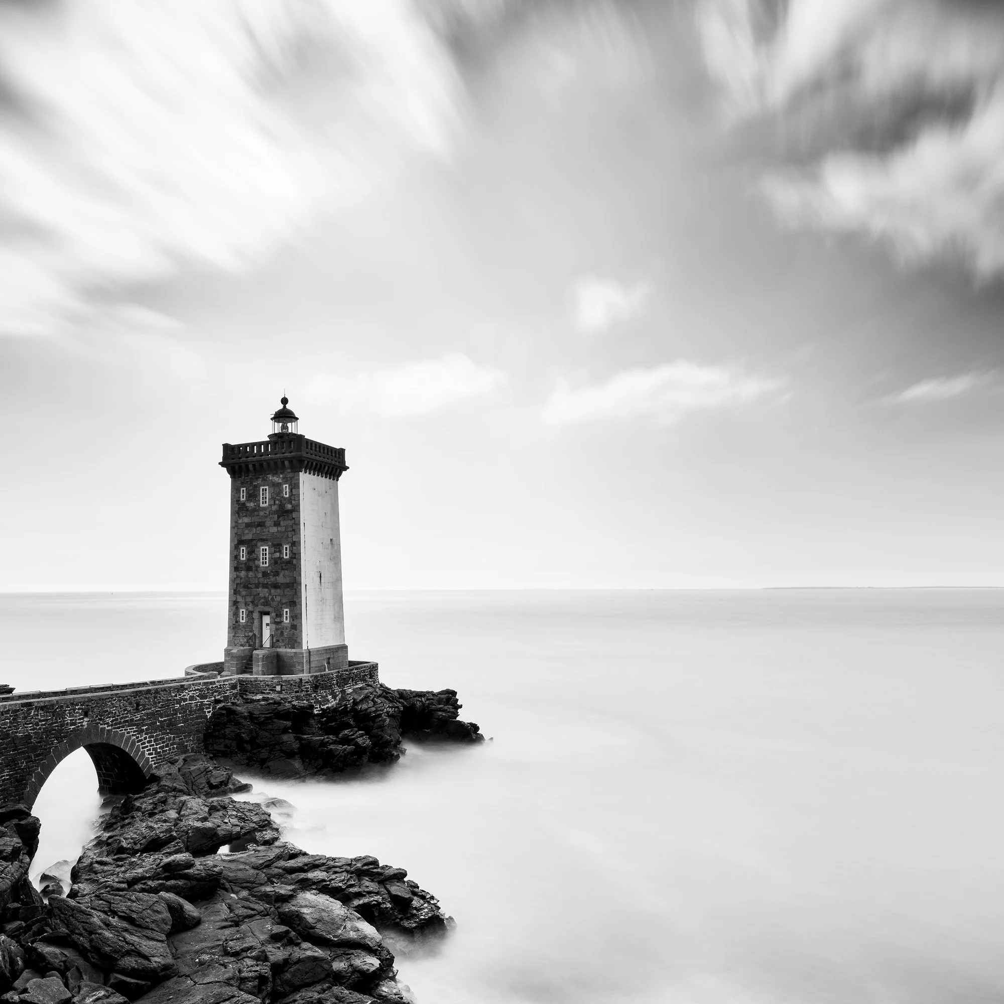 Lighthouse of Kermorvan by Gerald Berghammer, black-and-white detail showing the lighthouse beneath sweeping long-exposure clouds.