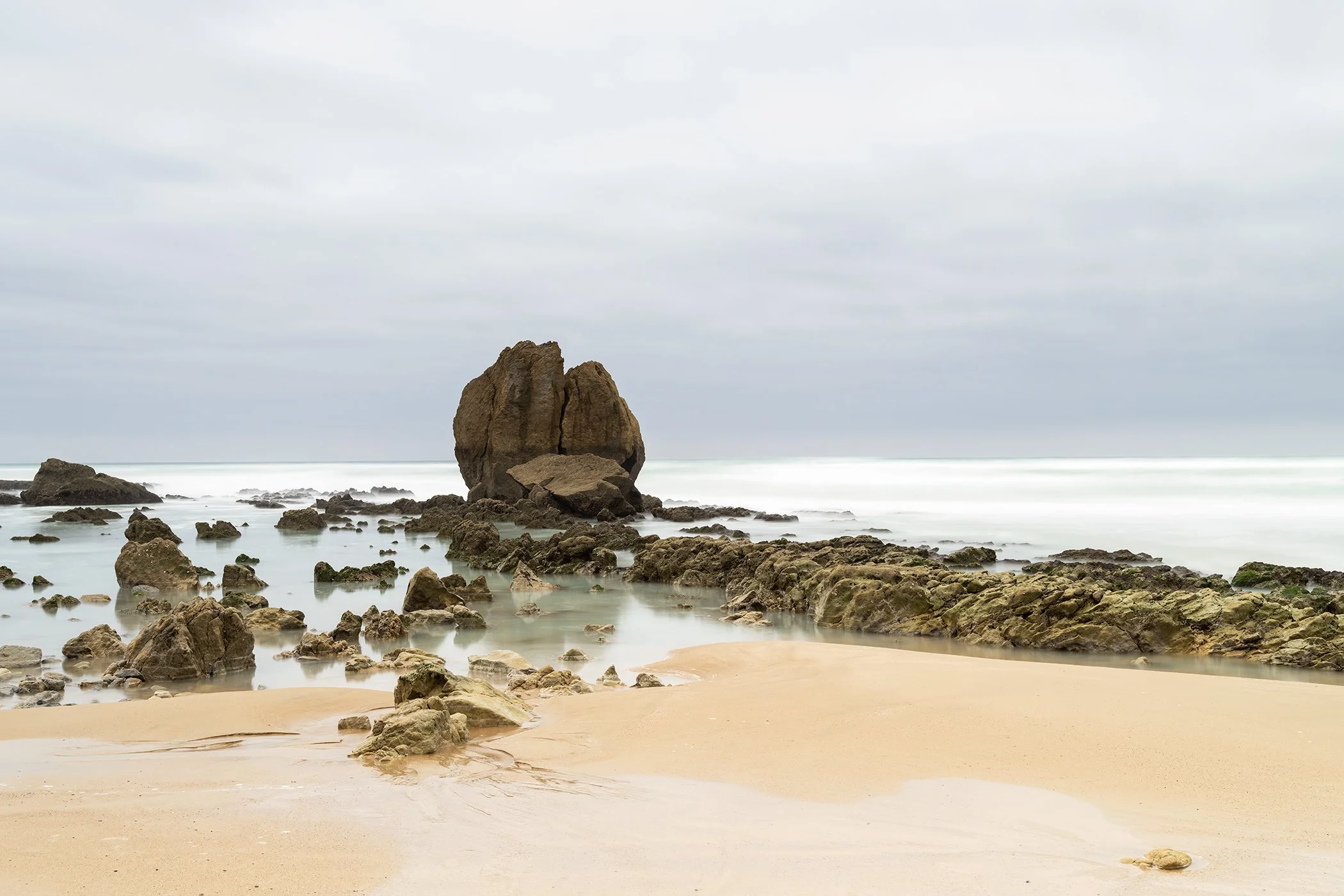 Minimalist colour seascape with sea stack, rocky beach and soft long-exposure water. Photo by Gerald Berghammer.