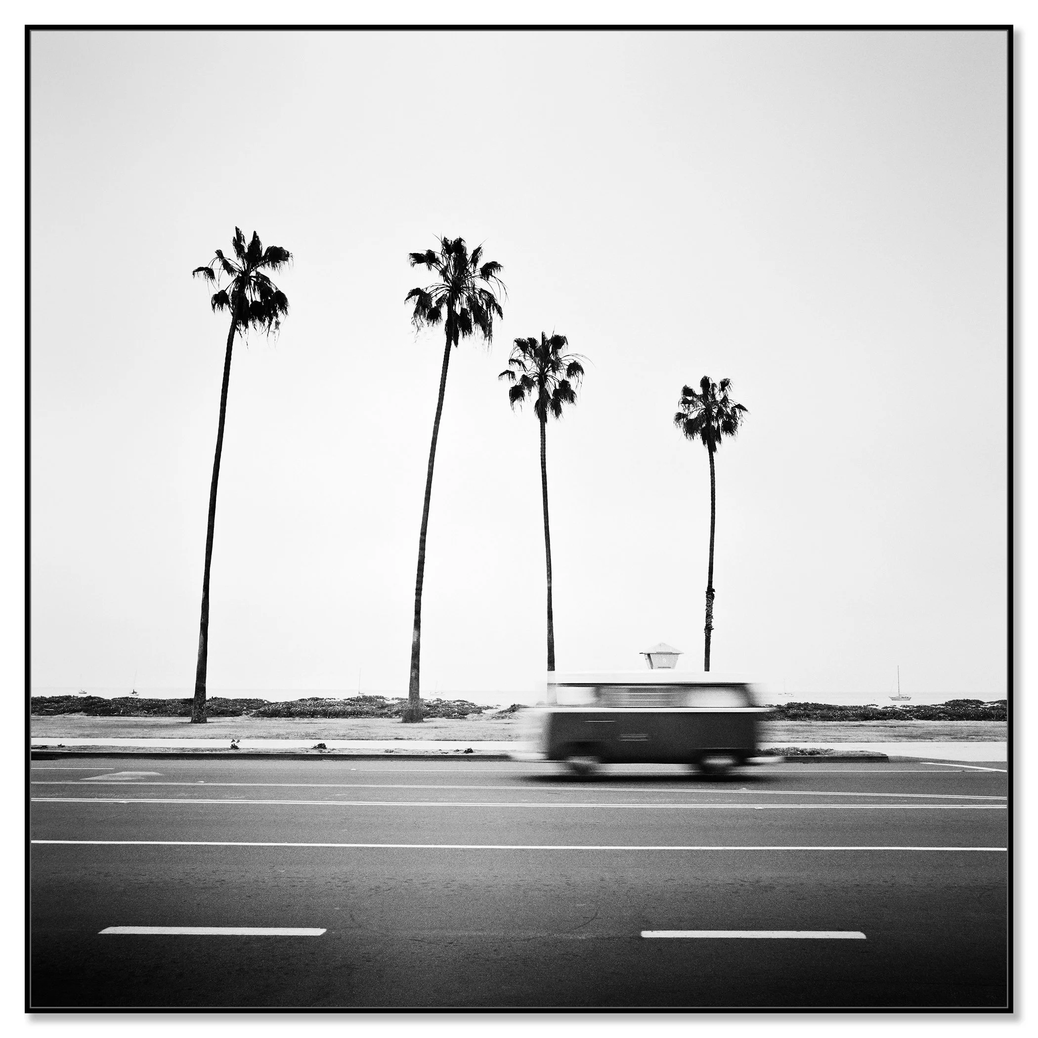 Black-and-white VW T2 bus with motion blur on a palm-lined coastal road in Santa Barbara, California – framed ArtBox black