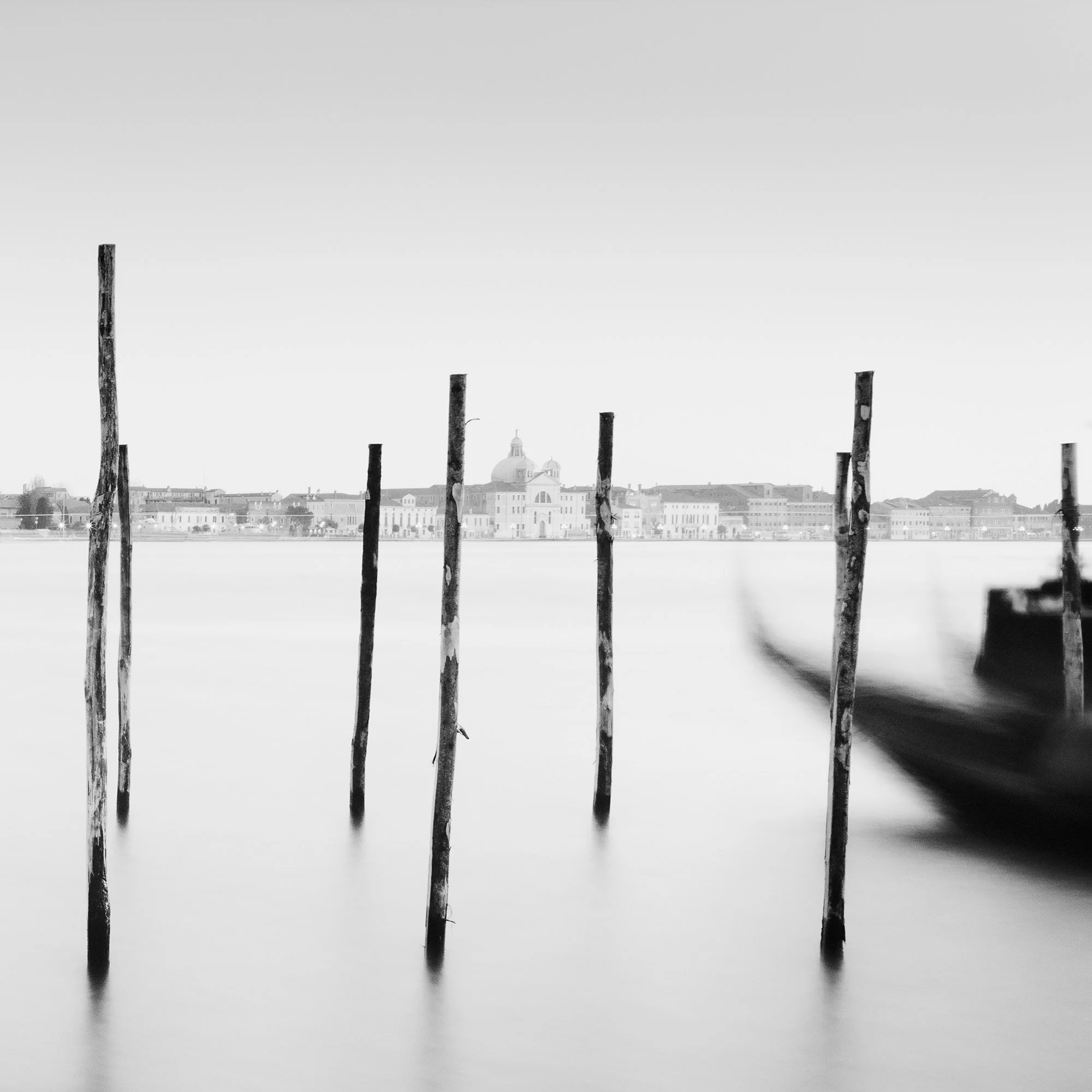 Detail of Basilica di San Giorgio Maggiore Panorama by Gerald Berghammer showing the Venetian Lagoon, mooring posts and a blurred gondola.