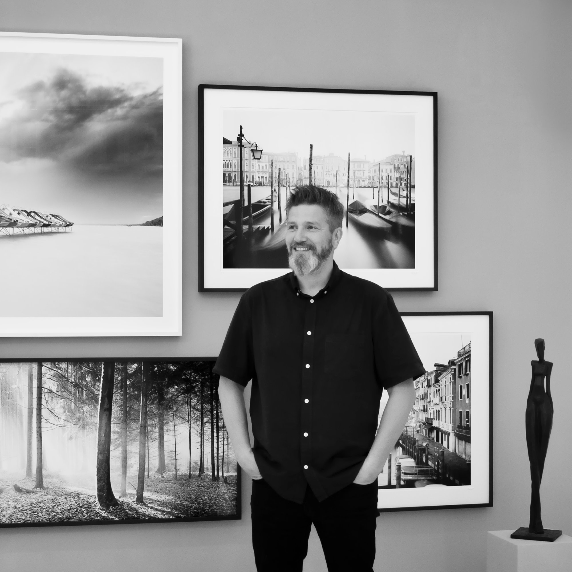 Gerald Berghammer in the SILVERFINEART space in Vienna, surrounded by his black-and-white fine art photographs and a bronze sculpture.