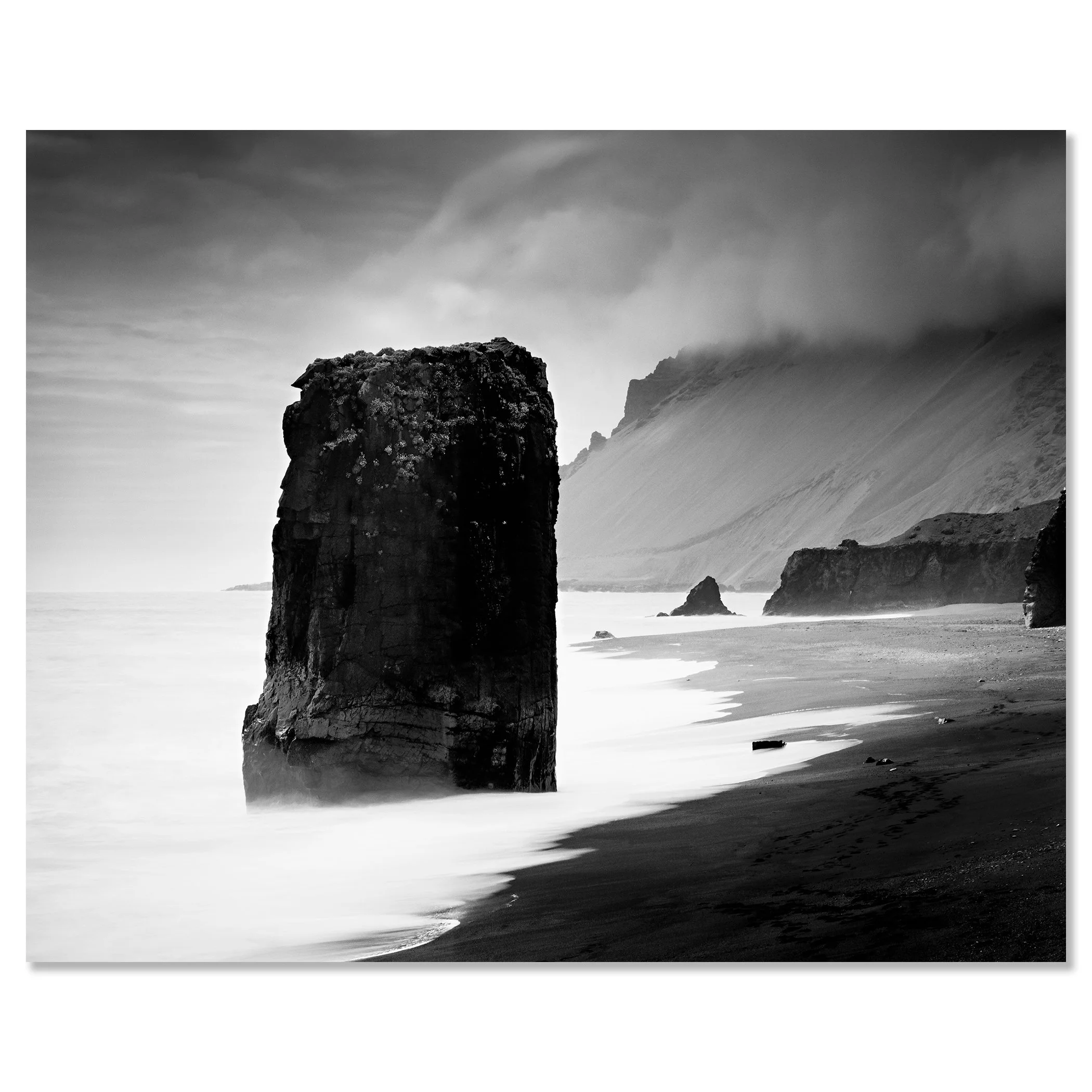 Gerald Berghammer - Black and white Photography. Coastal landscape featuring large sea stacks, sandy shoreline and cliffs with mist over the distant hills. Chromaluxe frameless