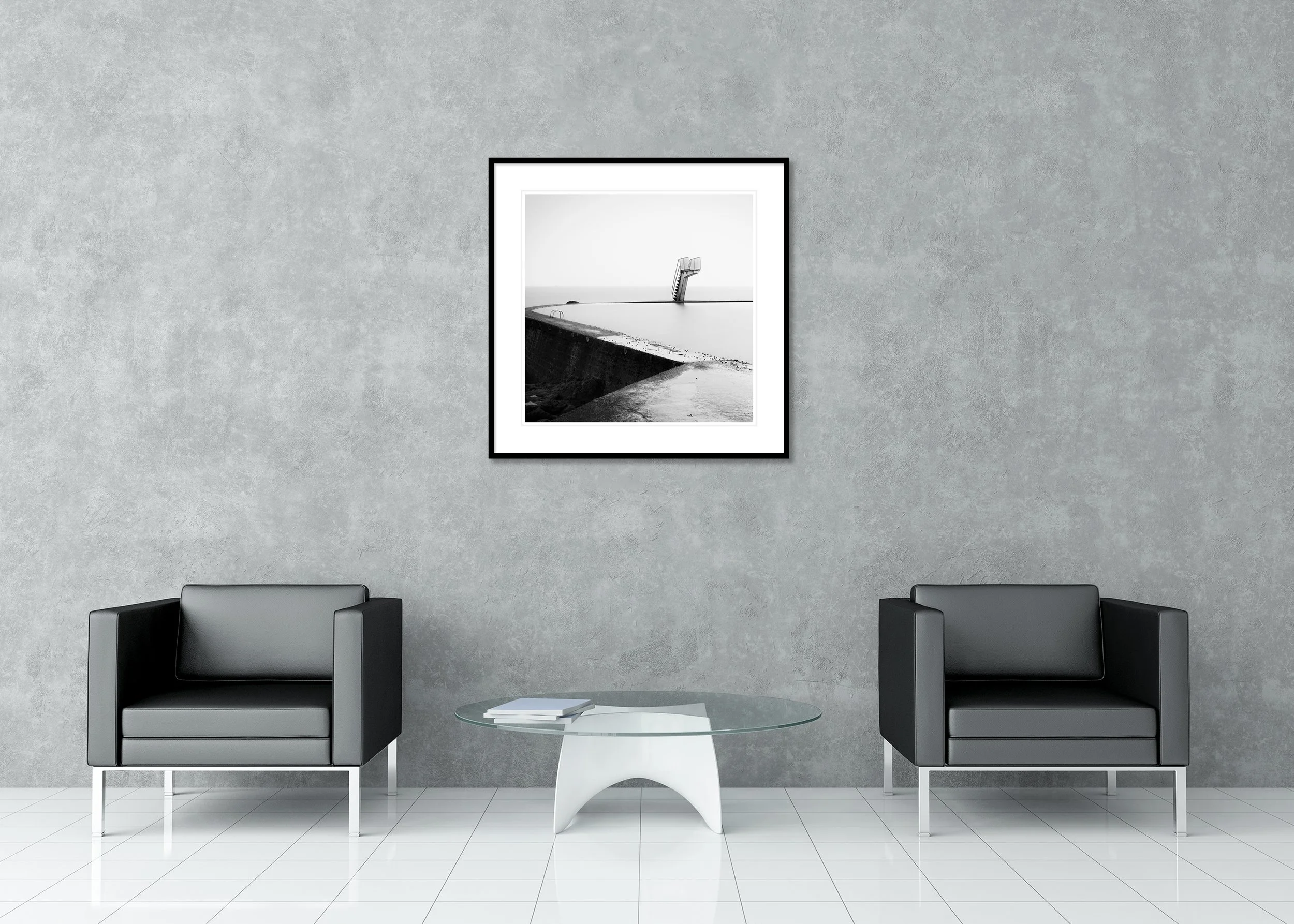 Black-and-white photograph of a calm seawater pool with a single diving platform, archival pigment print in a classic frame with a mount.