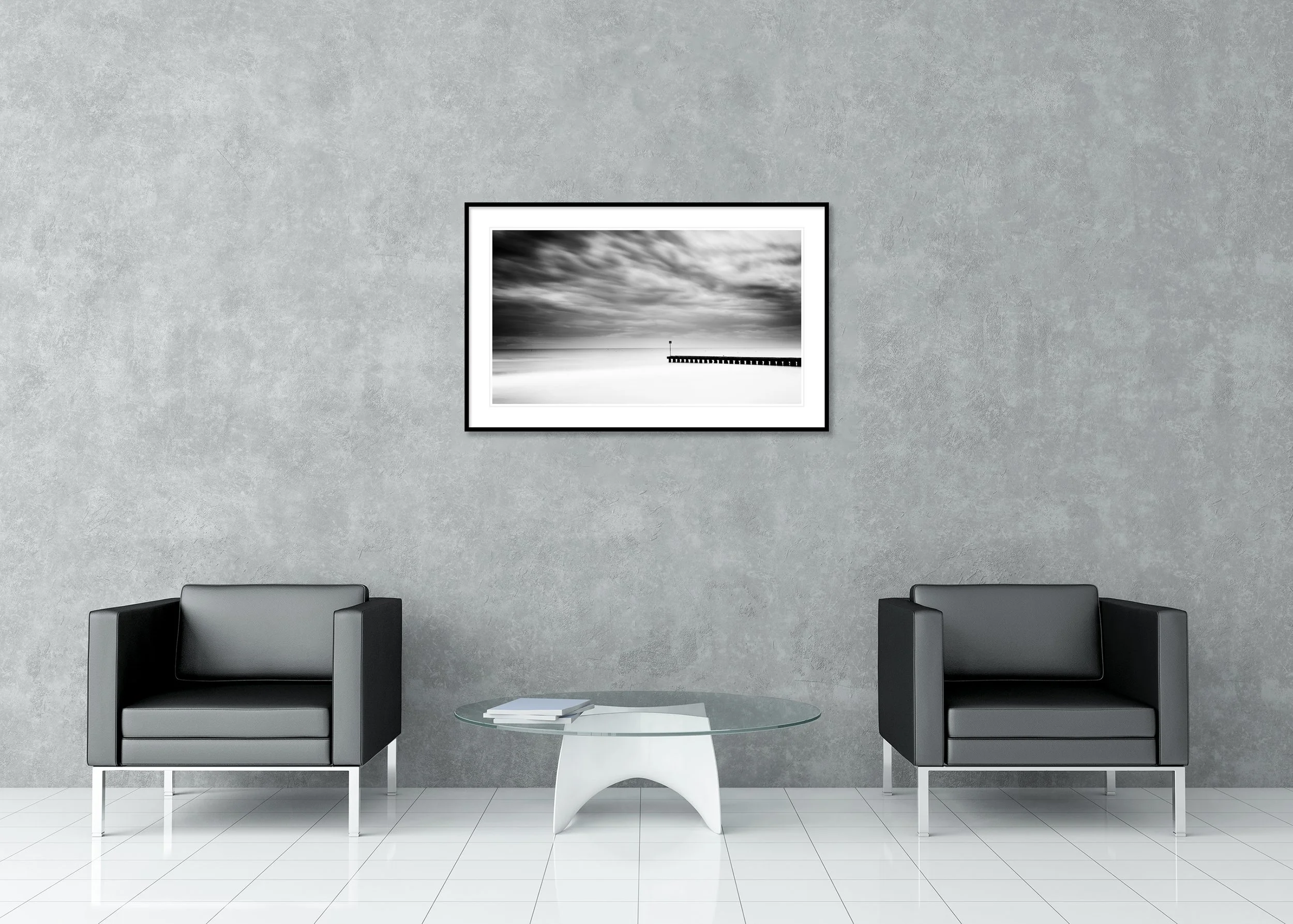 Black and white seascape with dramatic clouds and a wooden pier over calm water, archival pigment print in a classic frame with a mount.