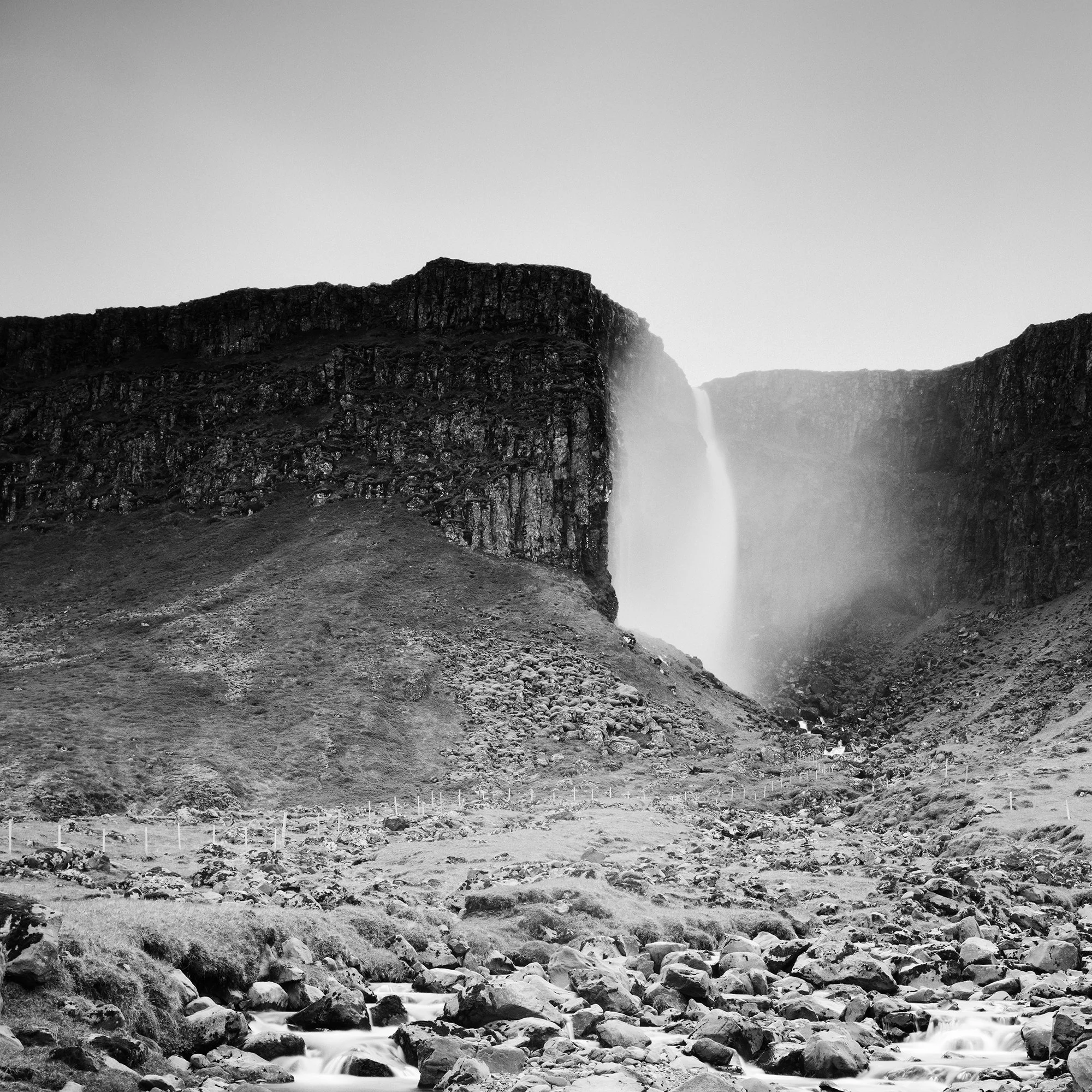 Gerald Berghammer - Black and white landscape photography. A waterfall cascading down a rocky cliff into a stream surrounded by rocks and rugged terrain. Print detail 2