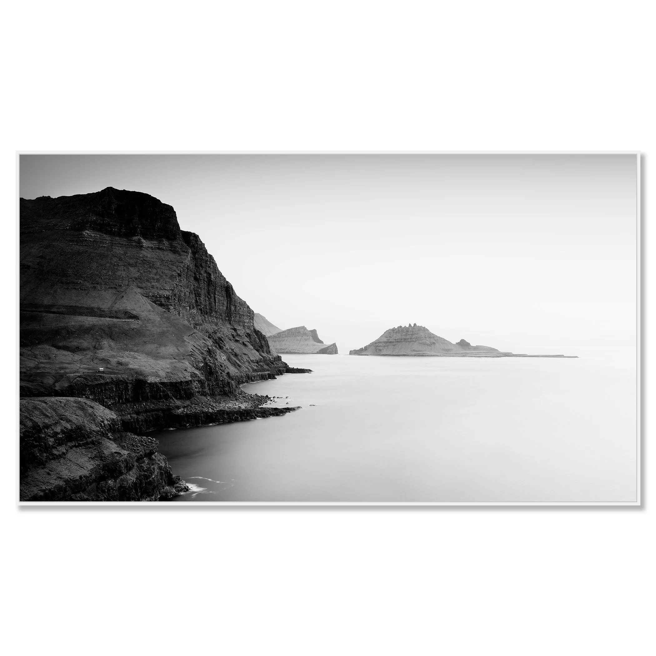 Black and white coastal landscape with steep cliffs and small rocky islands in calm sea – framed ArtBox white