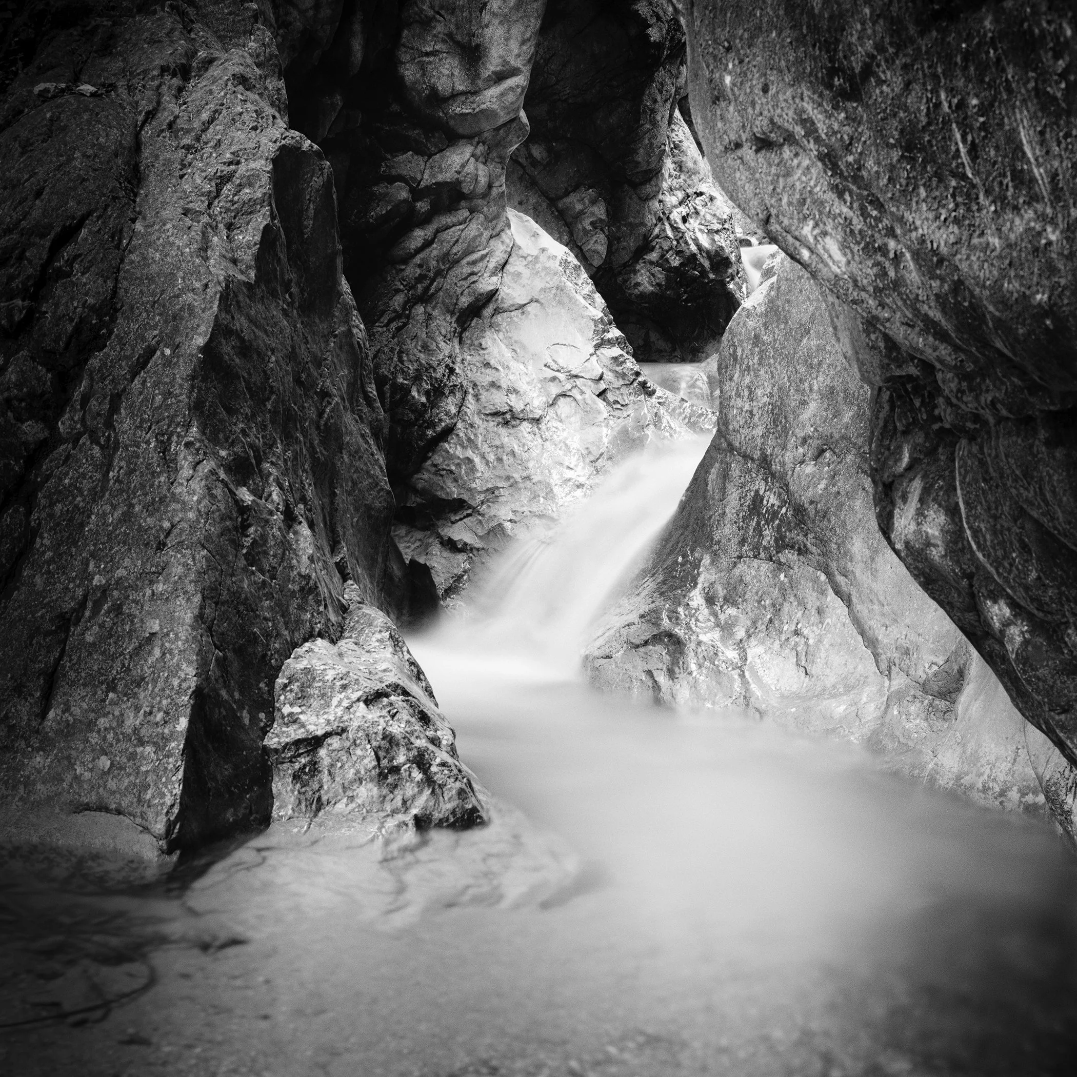 Fine art black-and-white photograph by Gerald Berghammer capturing soft flowing water through a rugged Austrian canyon.