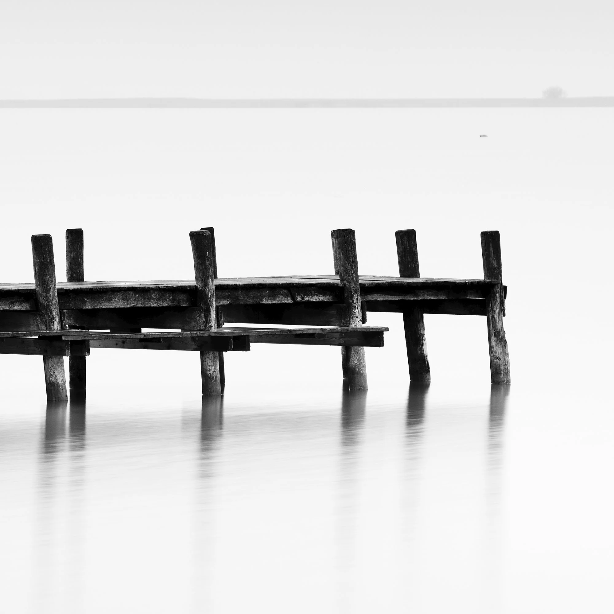 © 2023 Gerald Berghammer - Black and white long exposure waterscape photo. Wooden pier extending into calm water, with a minimalistic and serene background. Print detail 3