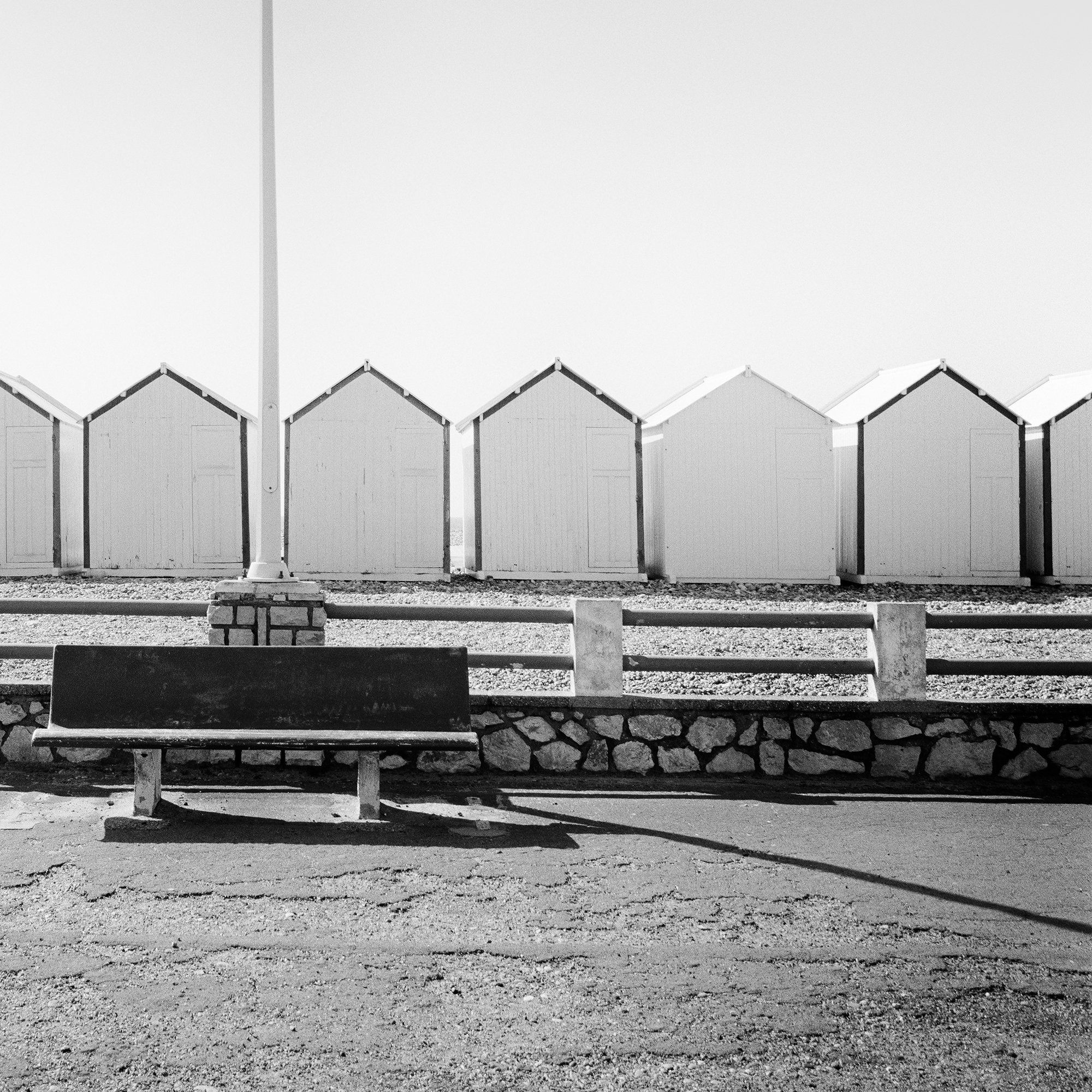Detail of Bench on the Promenade Study 1 showing the bench, streetlamp and right-hand beach huts in France by Gerald Berghammer.