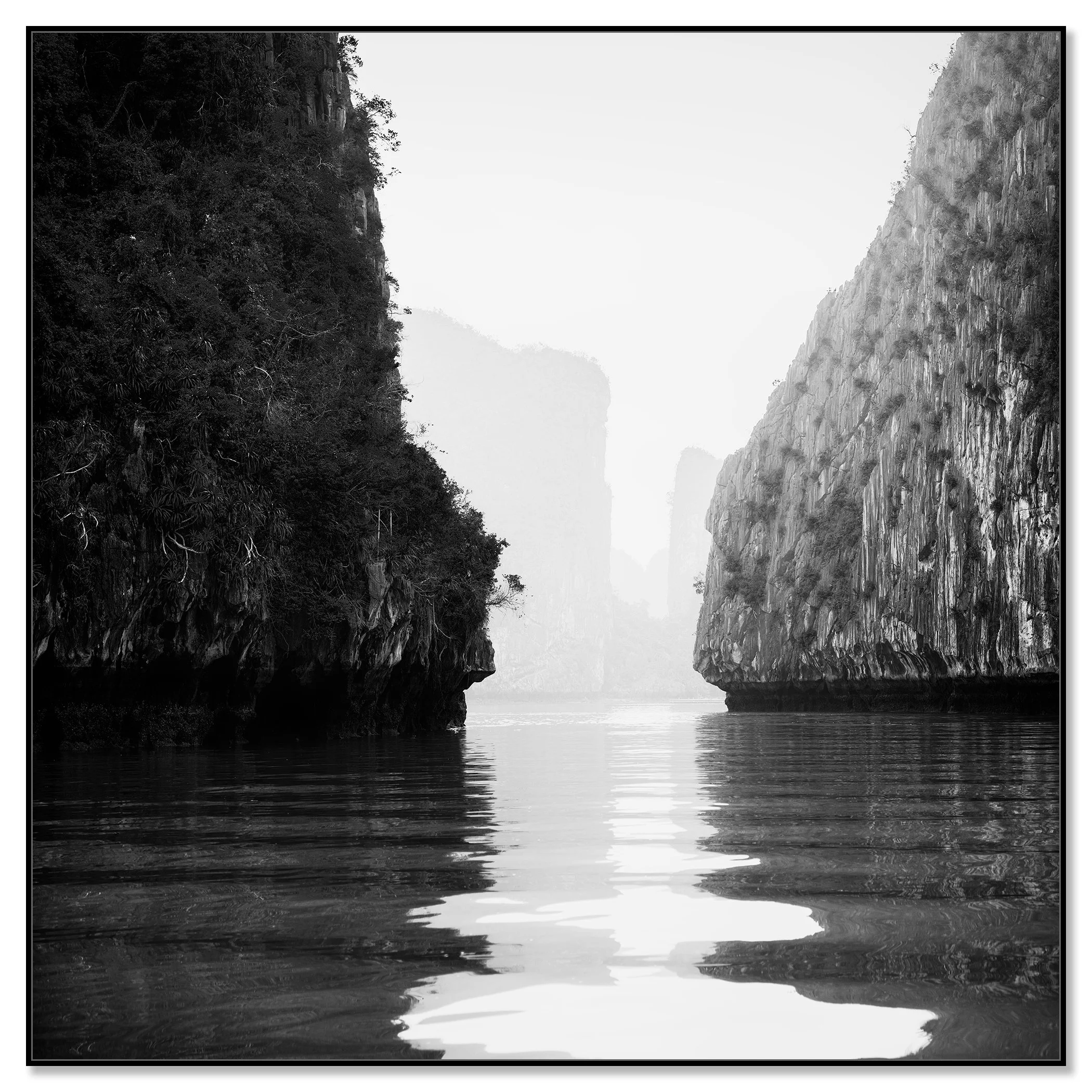 Karst limestone cliffs mirrored in calm water, black-and-white fine art photo, Ha Long Bay – framed ArtBox black