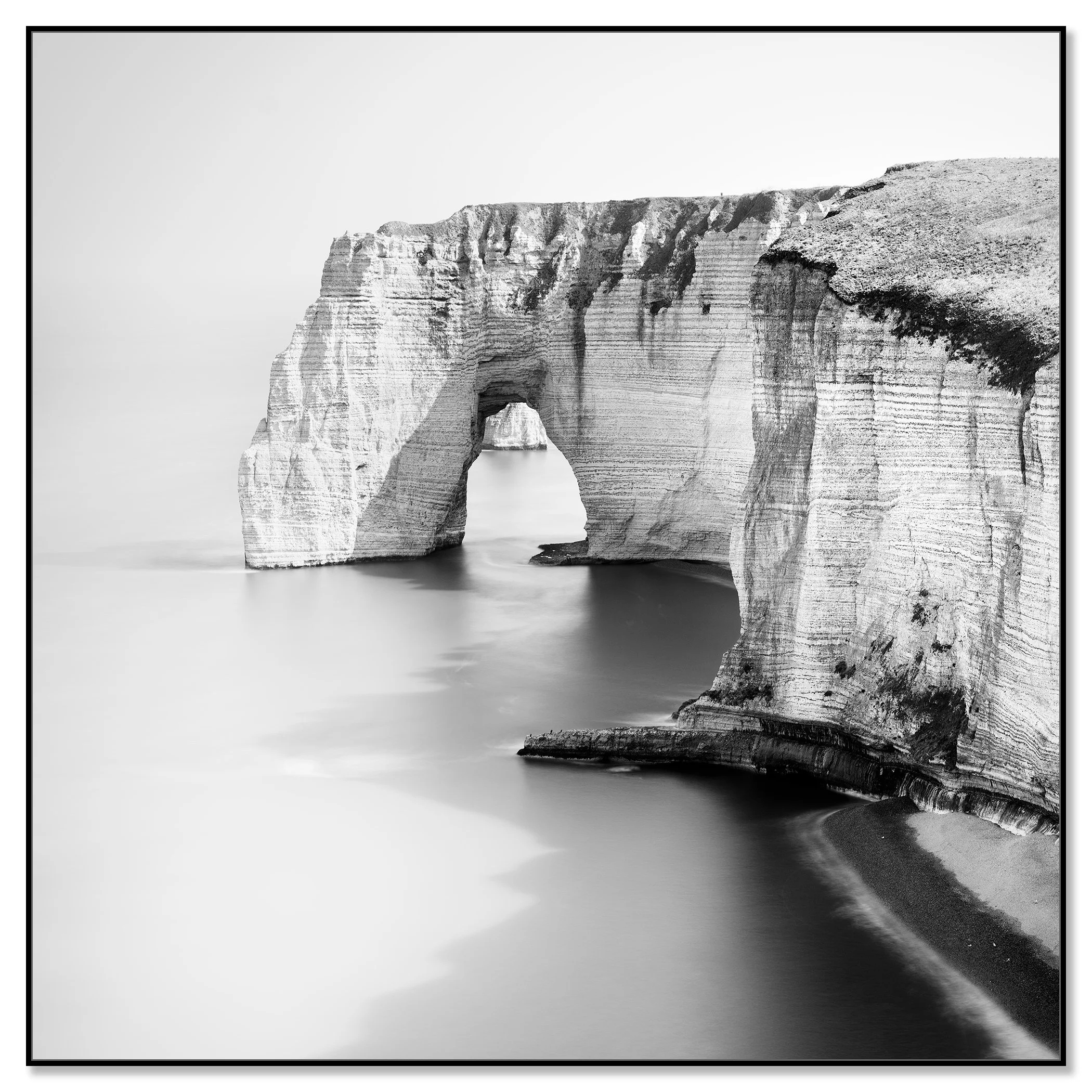 Black and white minimalist seascape photo of a natural rock arch over the water on a rugged coastline – framed ArtBox black