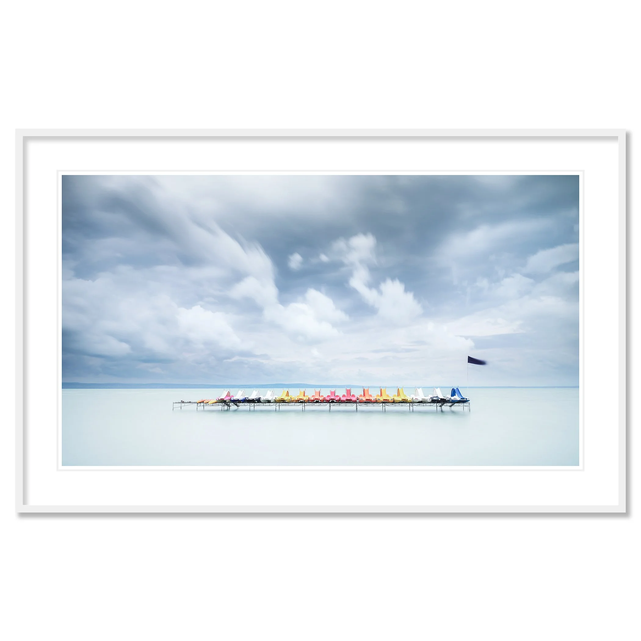 Gerald Berghammer - Color long exposure waterscape photography. Colorful paddle boats lined up on a dock over calm water, under a cloudy sky. Classic framed white