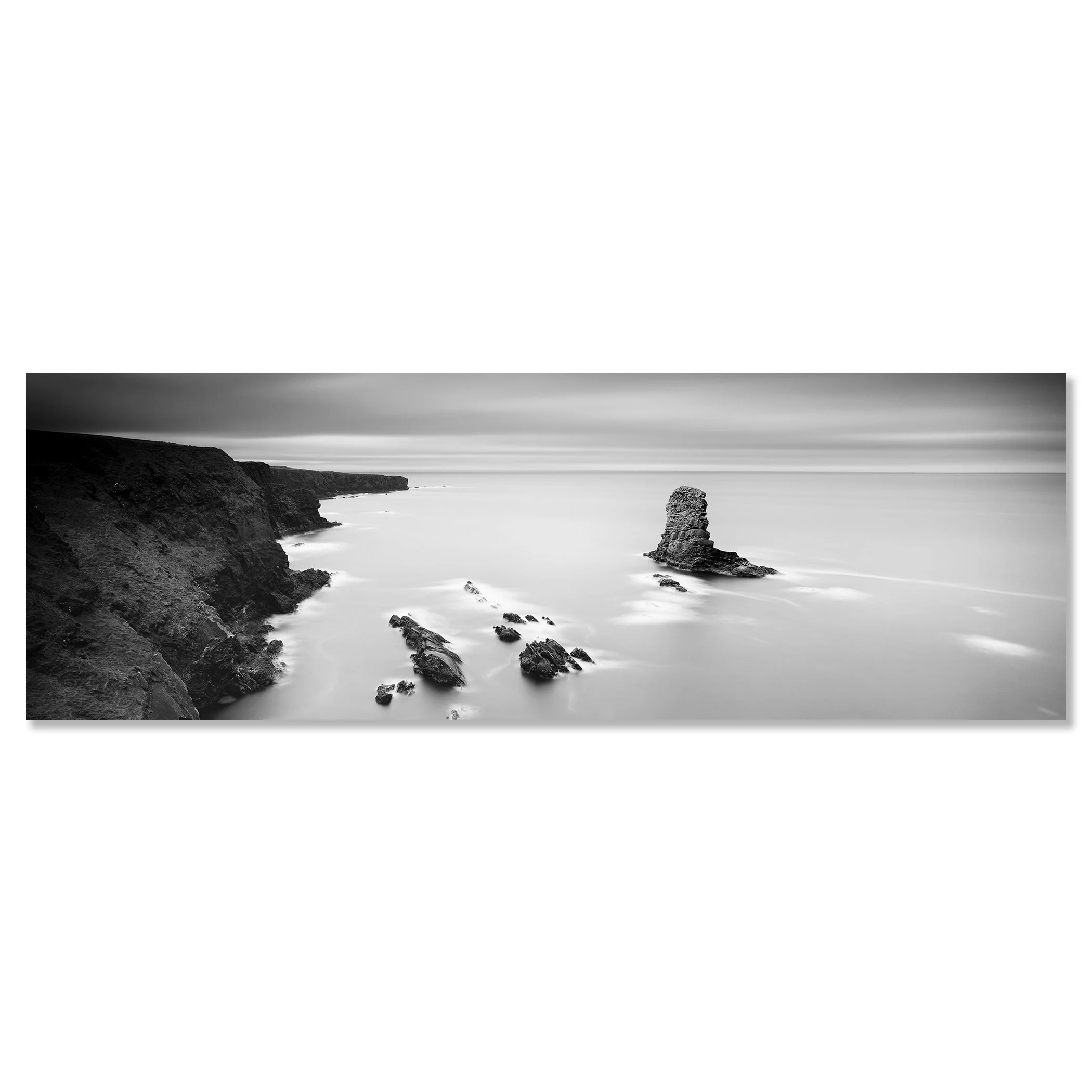 Gerald Berghammer - Black and white panorama seascape photography. Rocky coastline with cliffs and a tall rock formation in the water, under a cloudy sky. Chromaluxe frameless