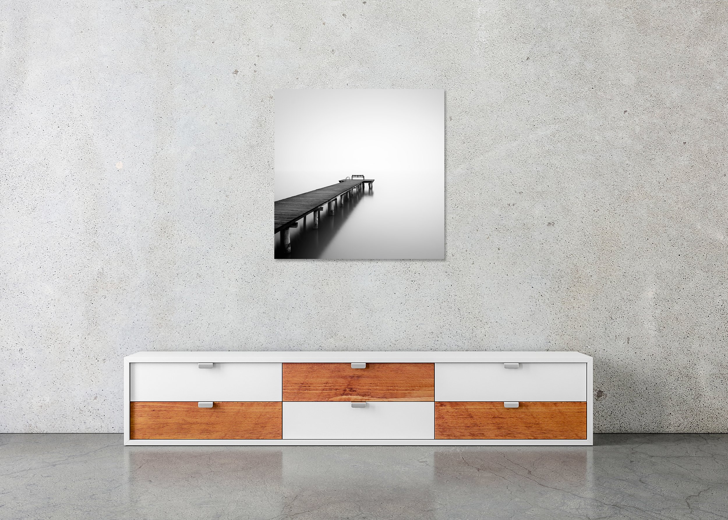 Minimalist black-and-white photograph of a pier stretching into foggy still water, with a bench at the end, mounted to Dibond, frameless.