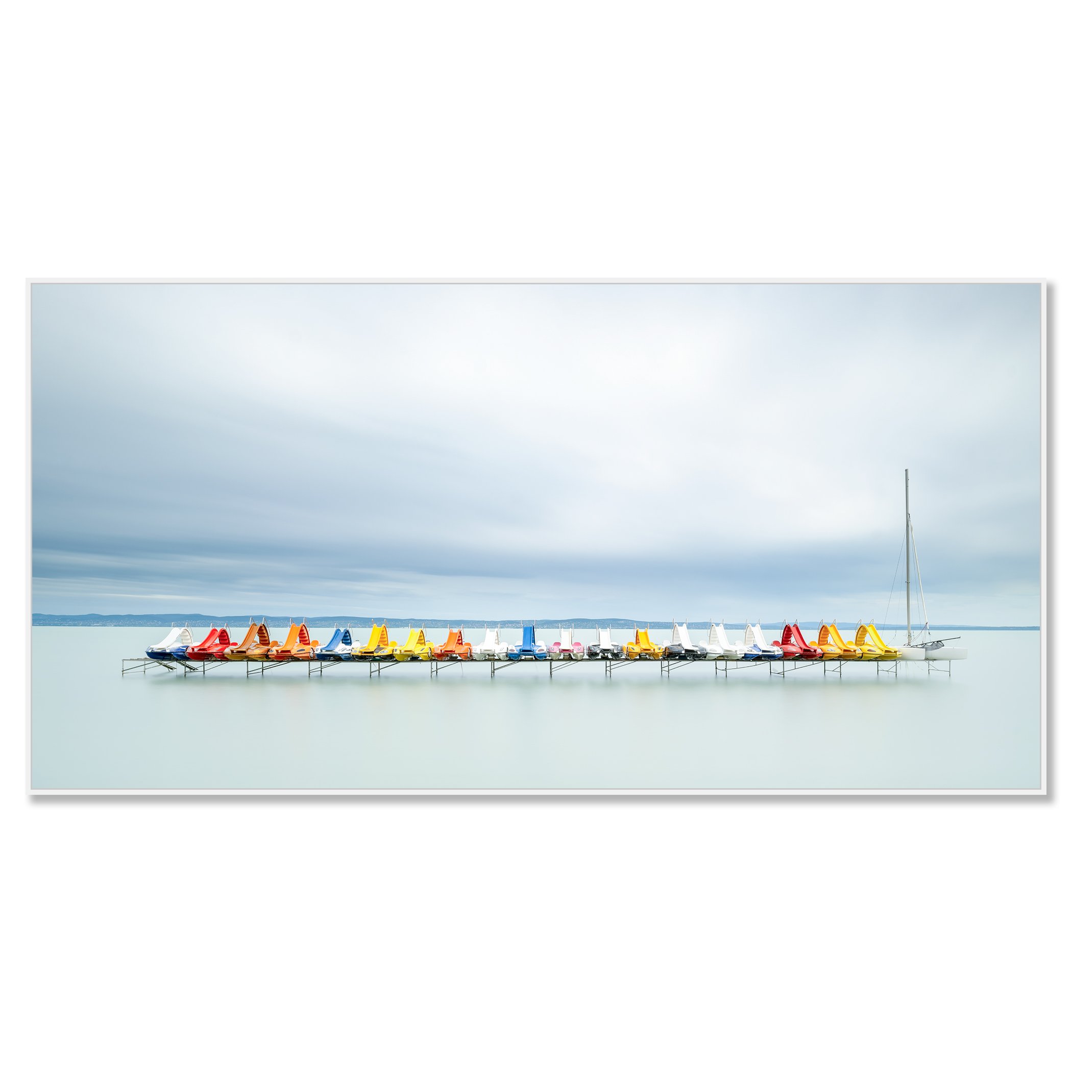 Gerald Berghammer - Color waterscape photography. Colorful pedal boats and a catamaran lined up on a dock on a calm body of water under a cloudy sky. Chromaluxe framed white