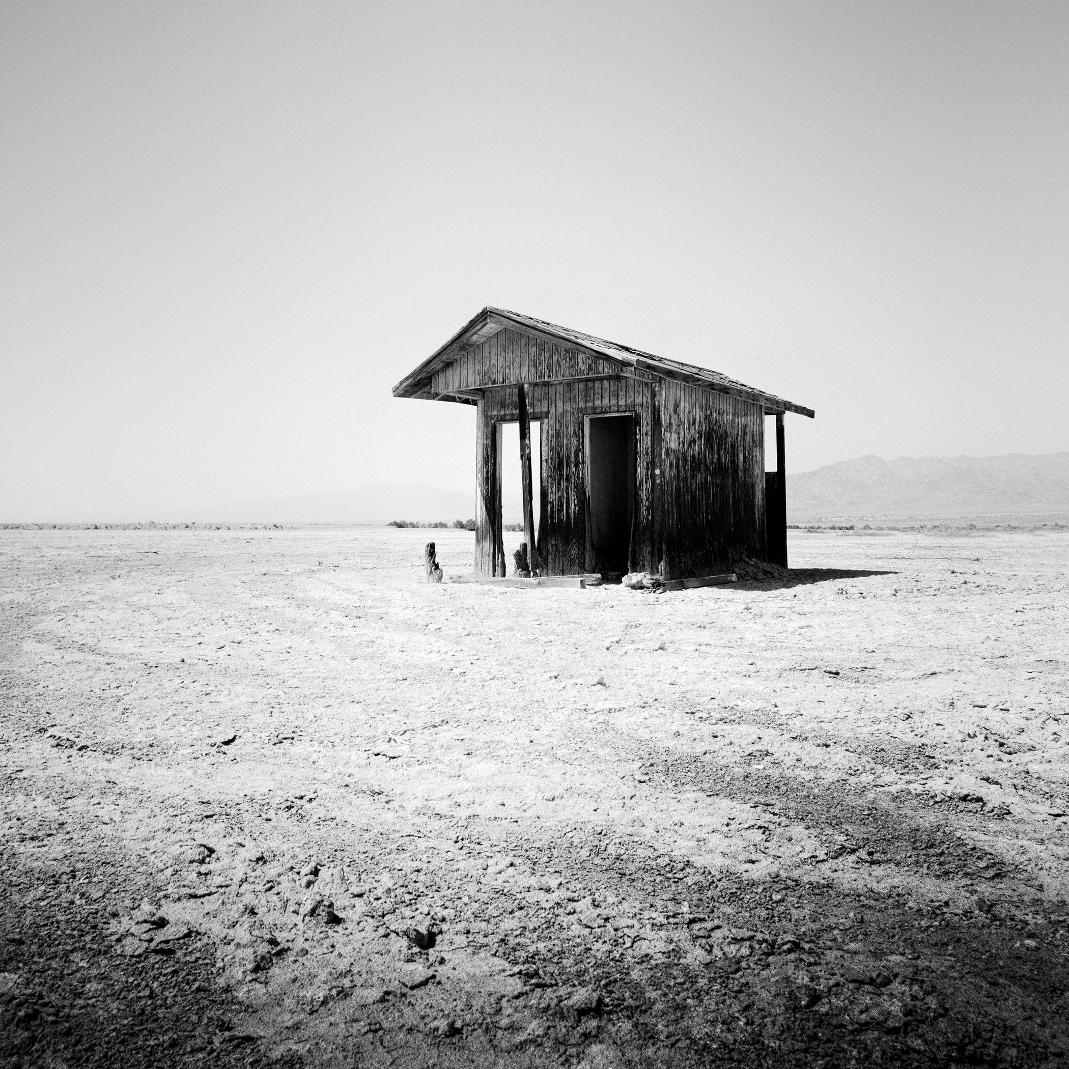 Bath House Study 1 by Gerald Berghammer, minimalist black-and-white analogue photograph of a solitary wooden hut near the Salton Sea, California.
