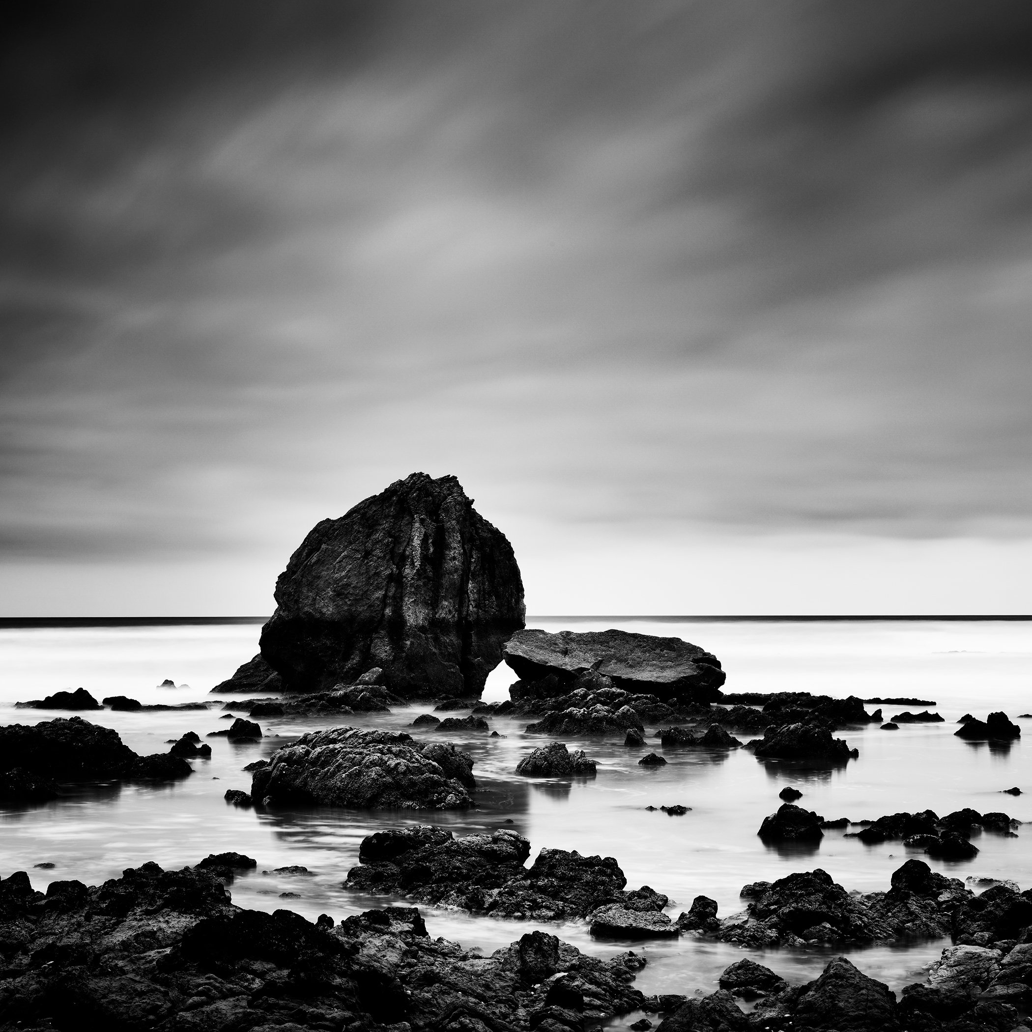 Beach Rock Study 1 – France, fine art black-and-white shoreline photograph with rock formations and long-exposure sea by Gerald Berghammer