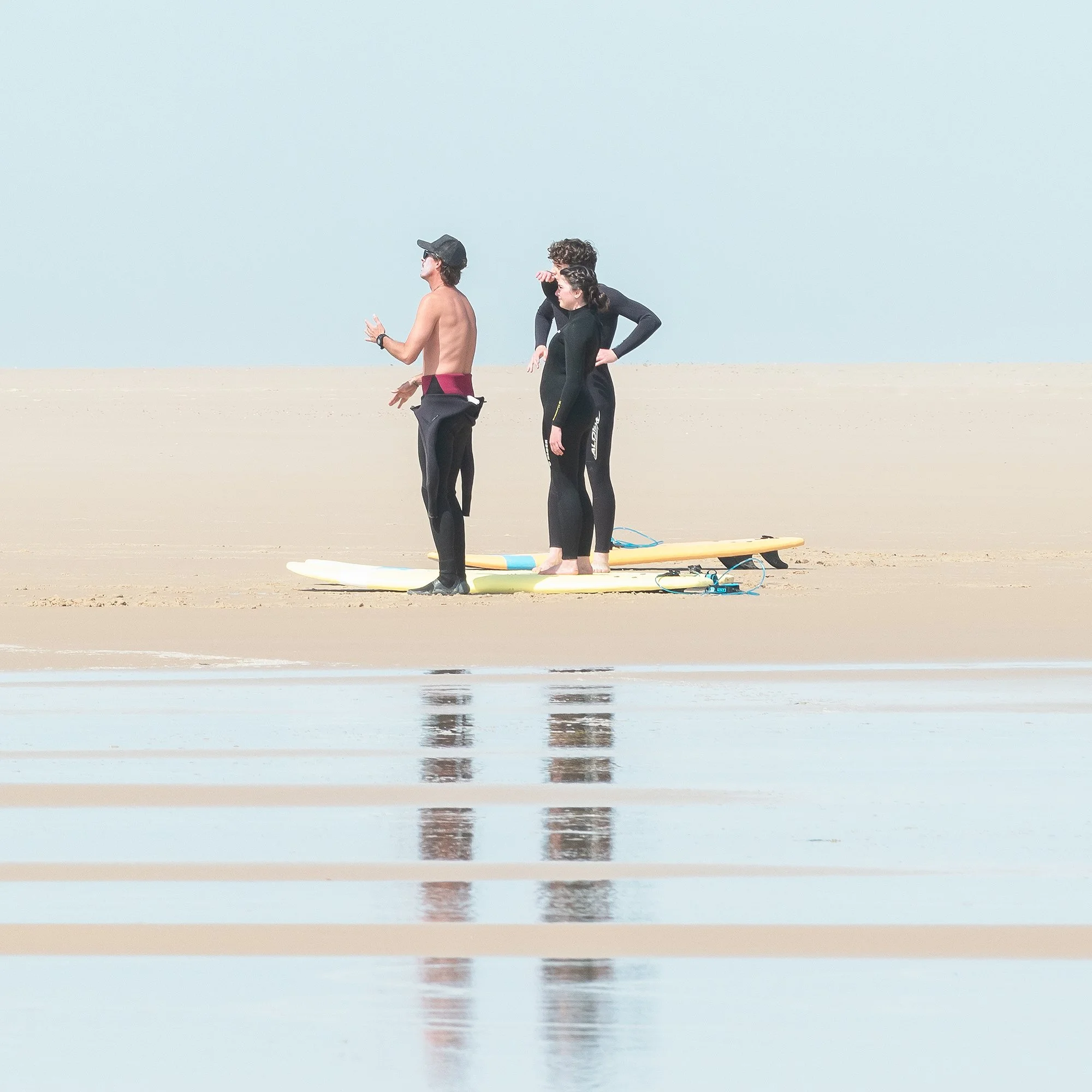 Detail of Wave Watcher, Study 1 – France, minimalist colour beach photograph with three surfers in open space. Photo by Gerald Berghammer.