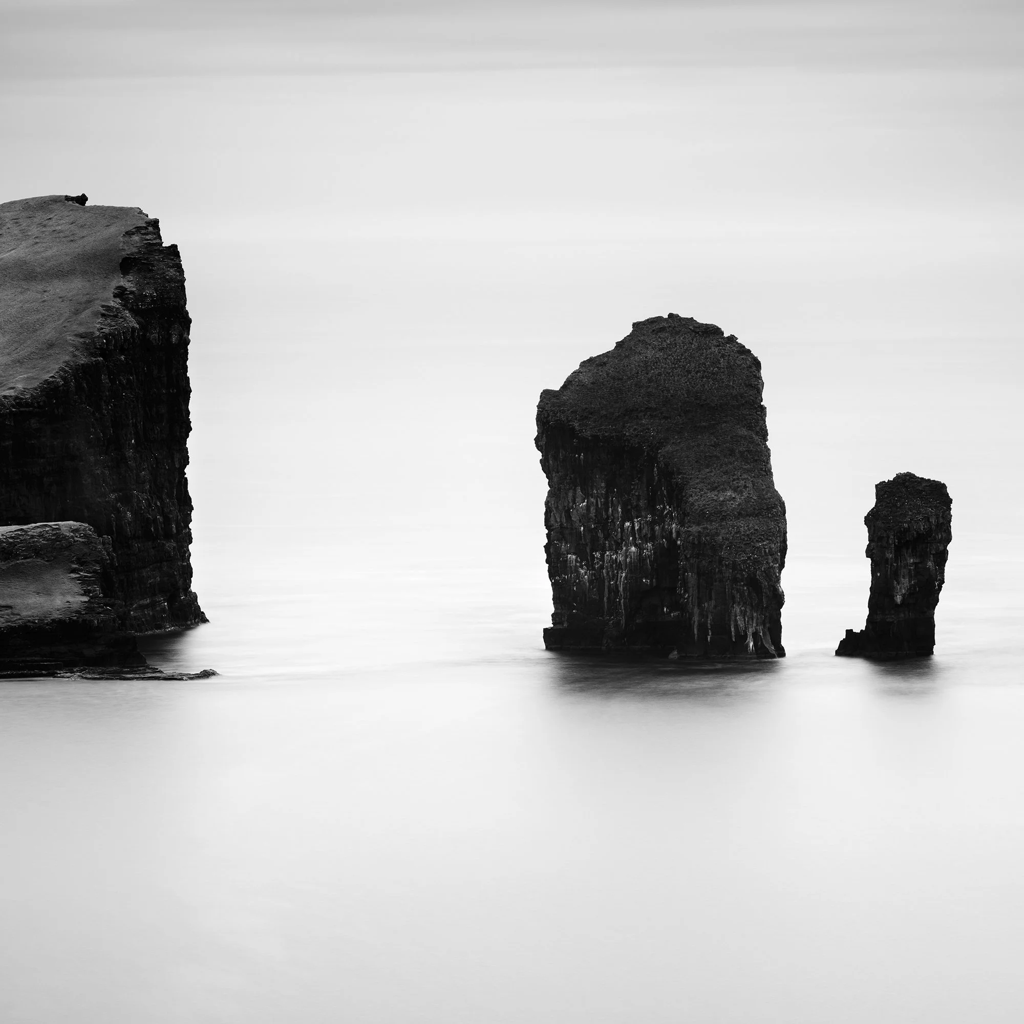 Cropped detail of North Atlantic Basalt Study 1 showing basalt cliff texture and long-exposure water in black and white.