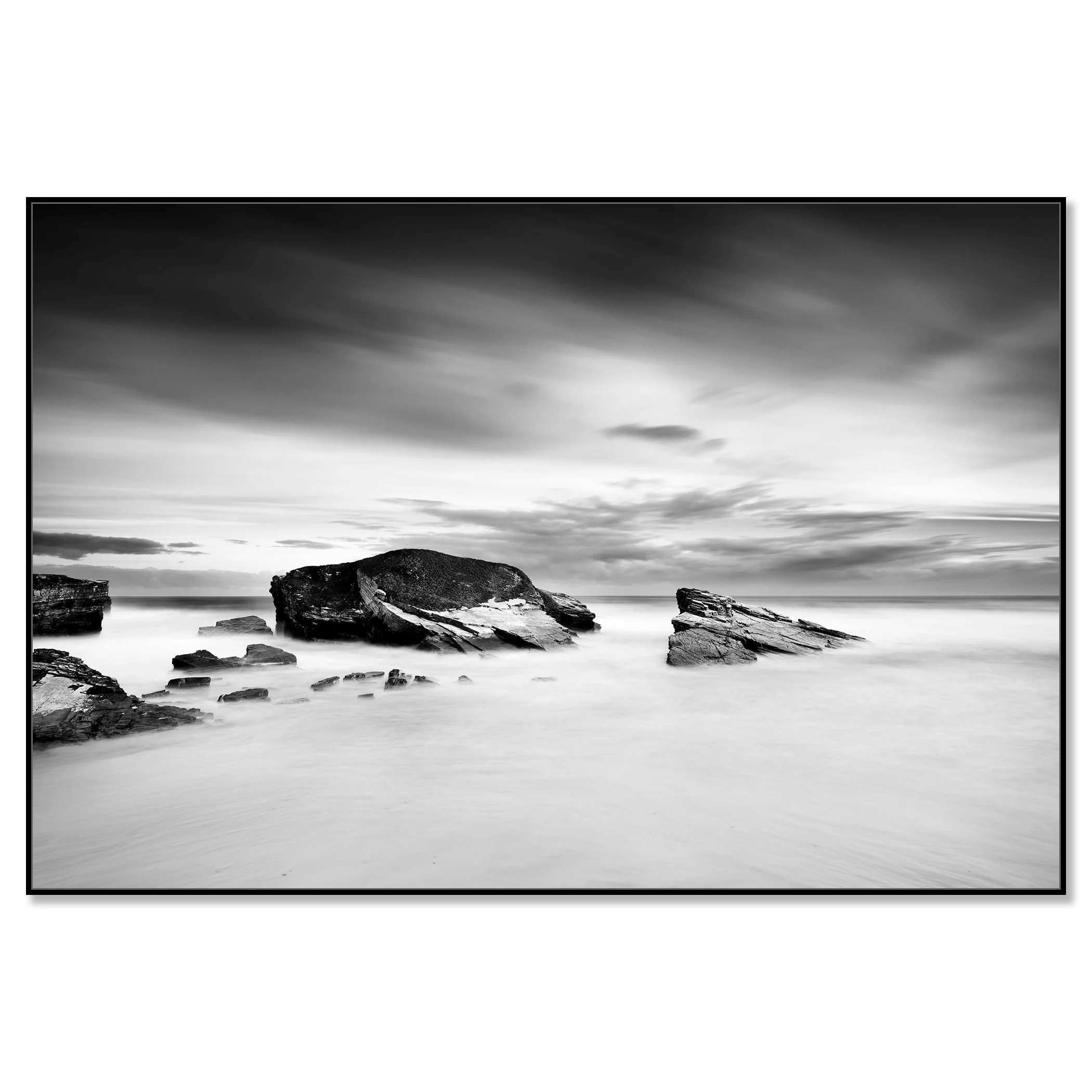 Monochrome long-exposure seascape with rocky coast and large rocks beneath overcast skies – framed ArtBox black