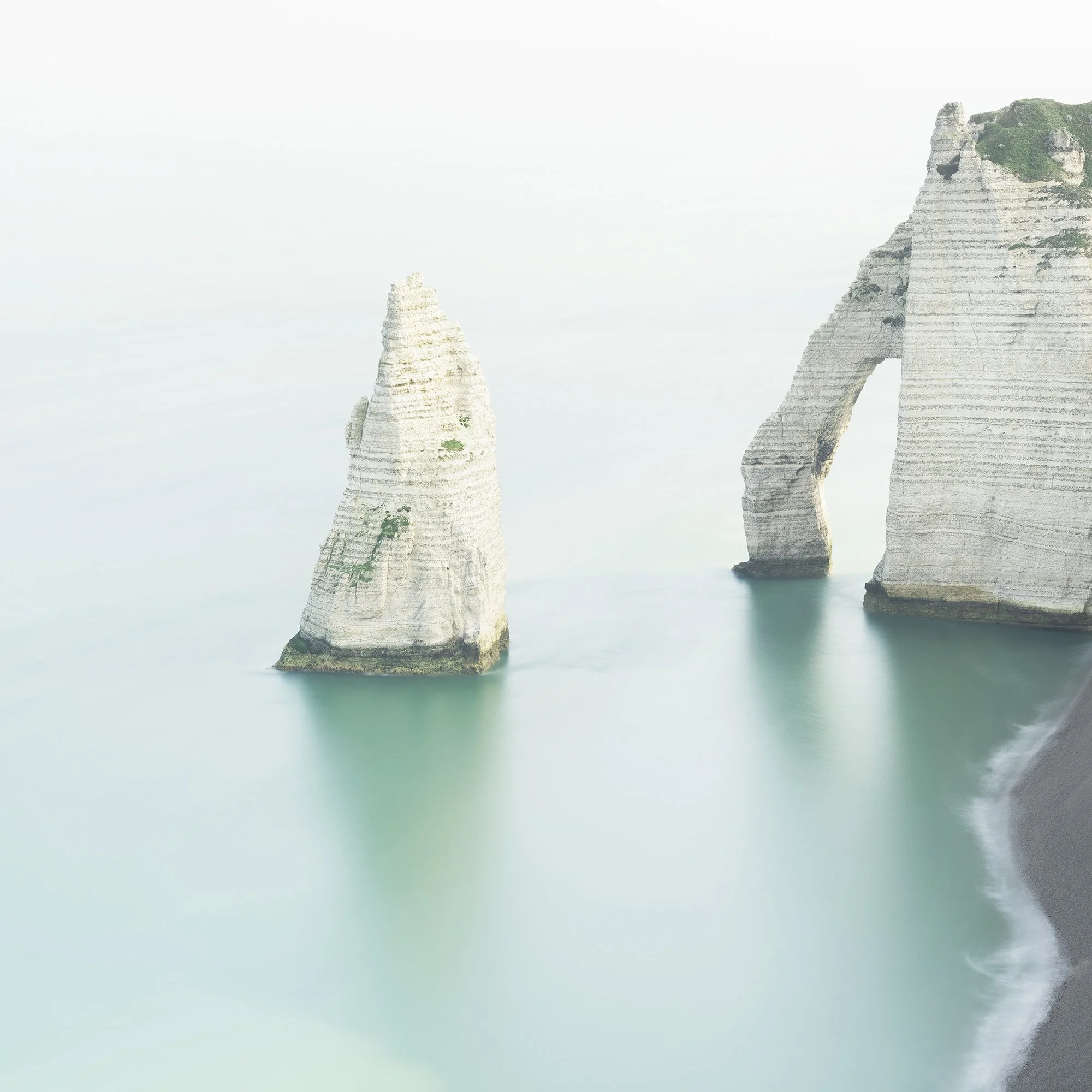 Detail of the chalk sea stack and soft turquoise water in The White Cliffs of Étretat