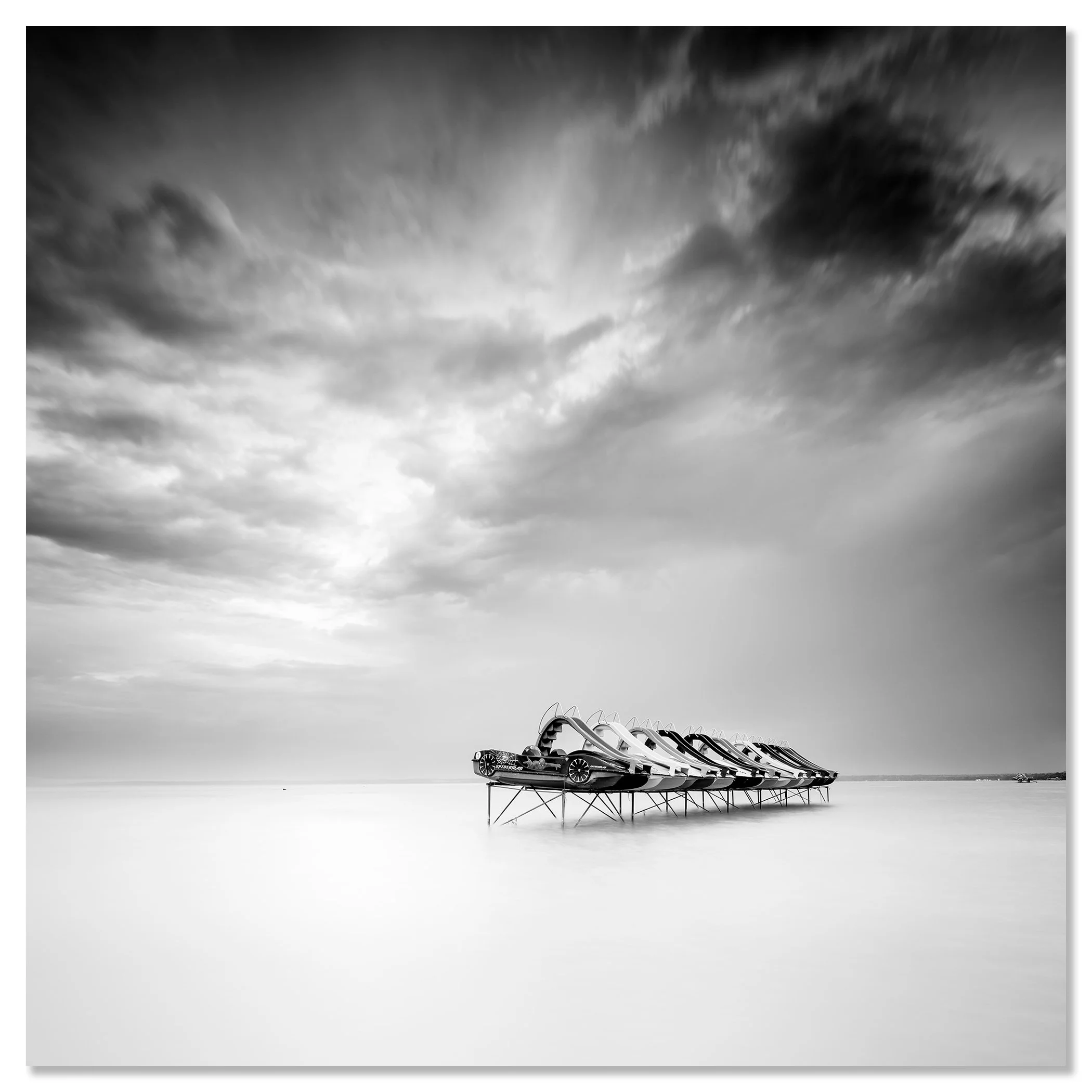nd white long-exposure lake scene with pedal boats on stilts and a dramatic cloudy sky – dibond frameless