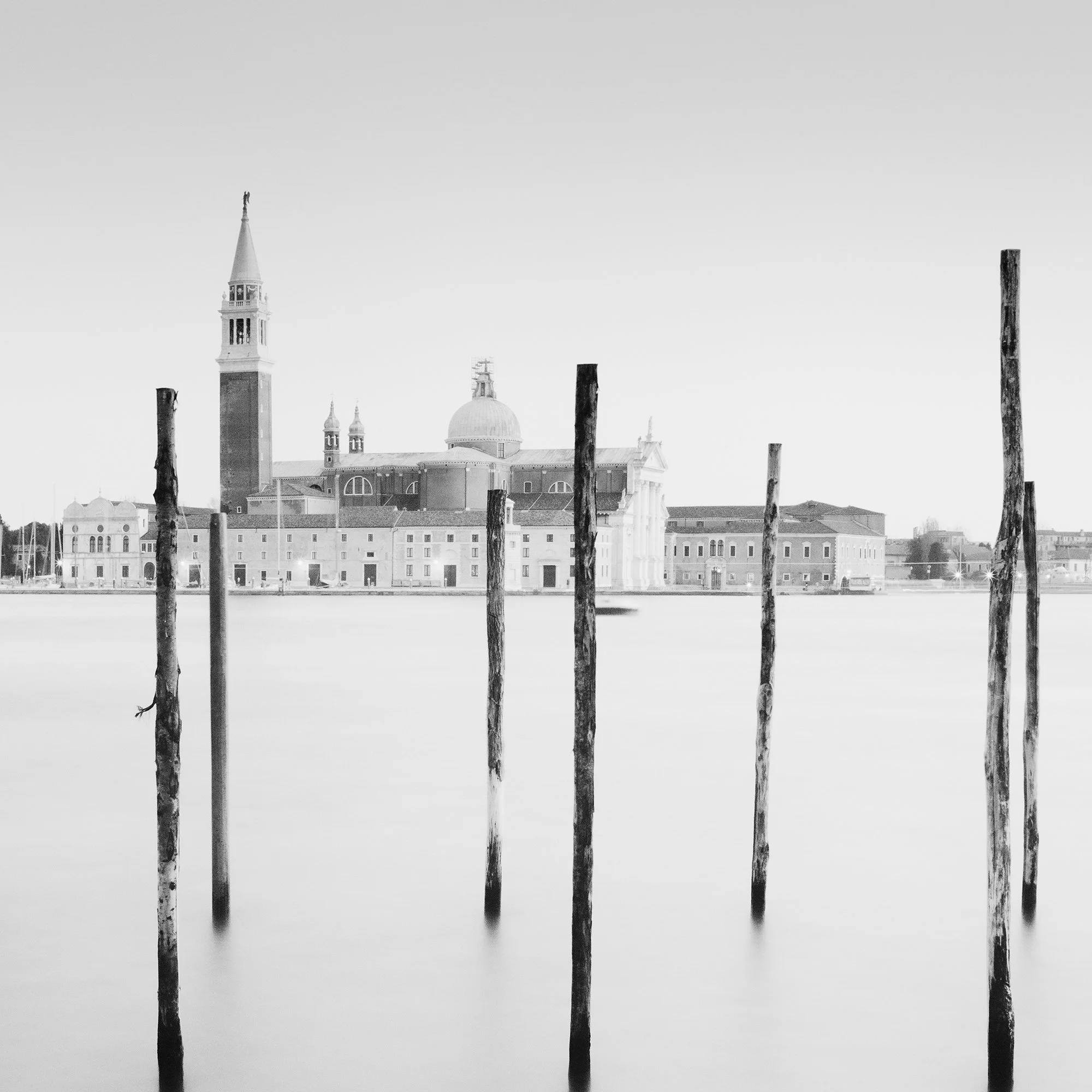 Detail of Basilica di San Giorgio Maggiore Panorama by Gerald Berghammer showing the basilica and wooden mooring posts in Venice.