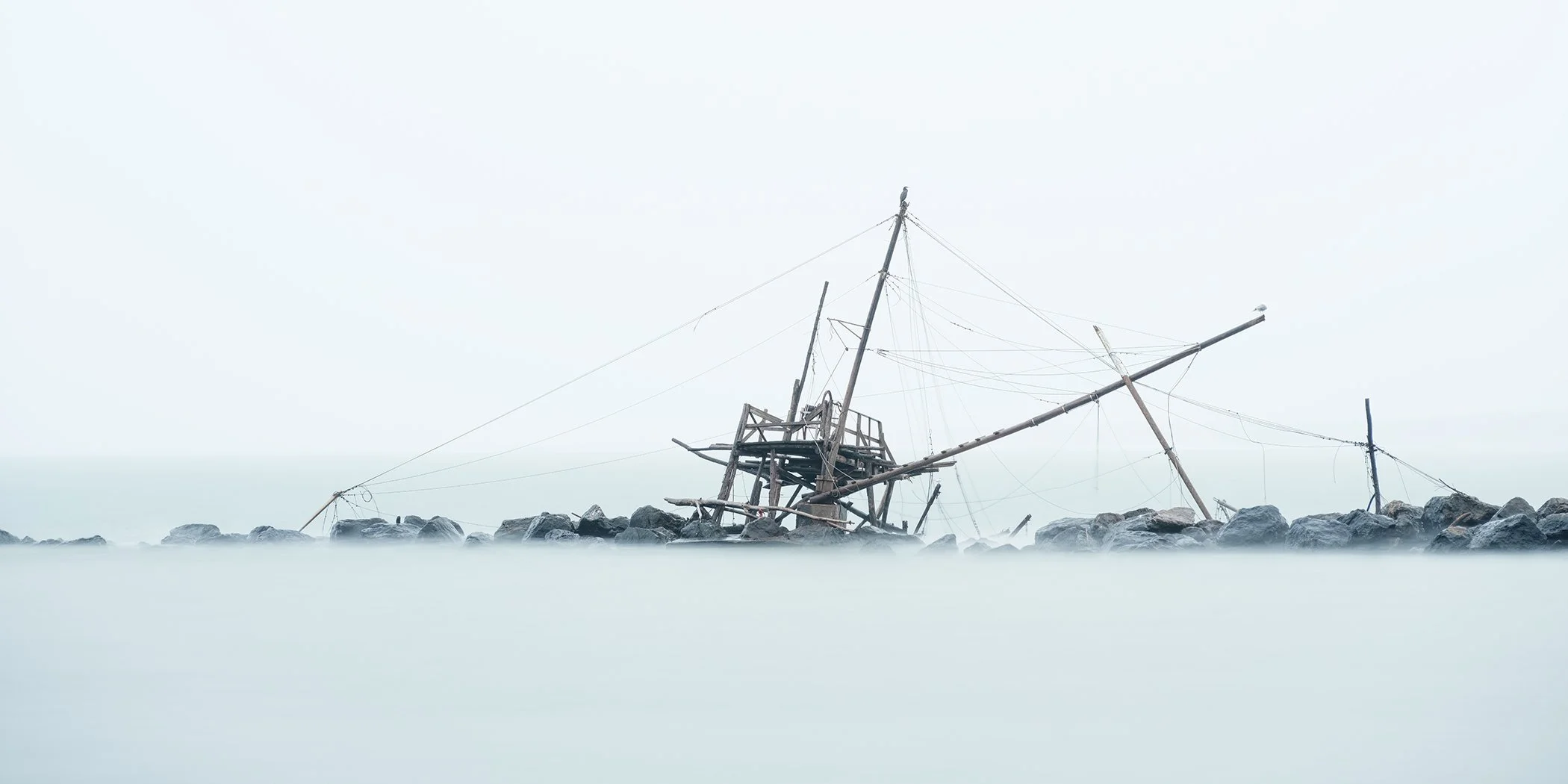 Minimalist colour photograph of a traditional wooden fishing platform in Marina di Pisa, Italy. Photo by Gerald Berghammer.