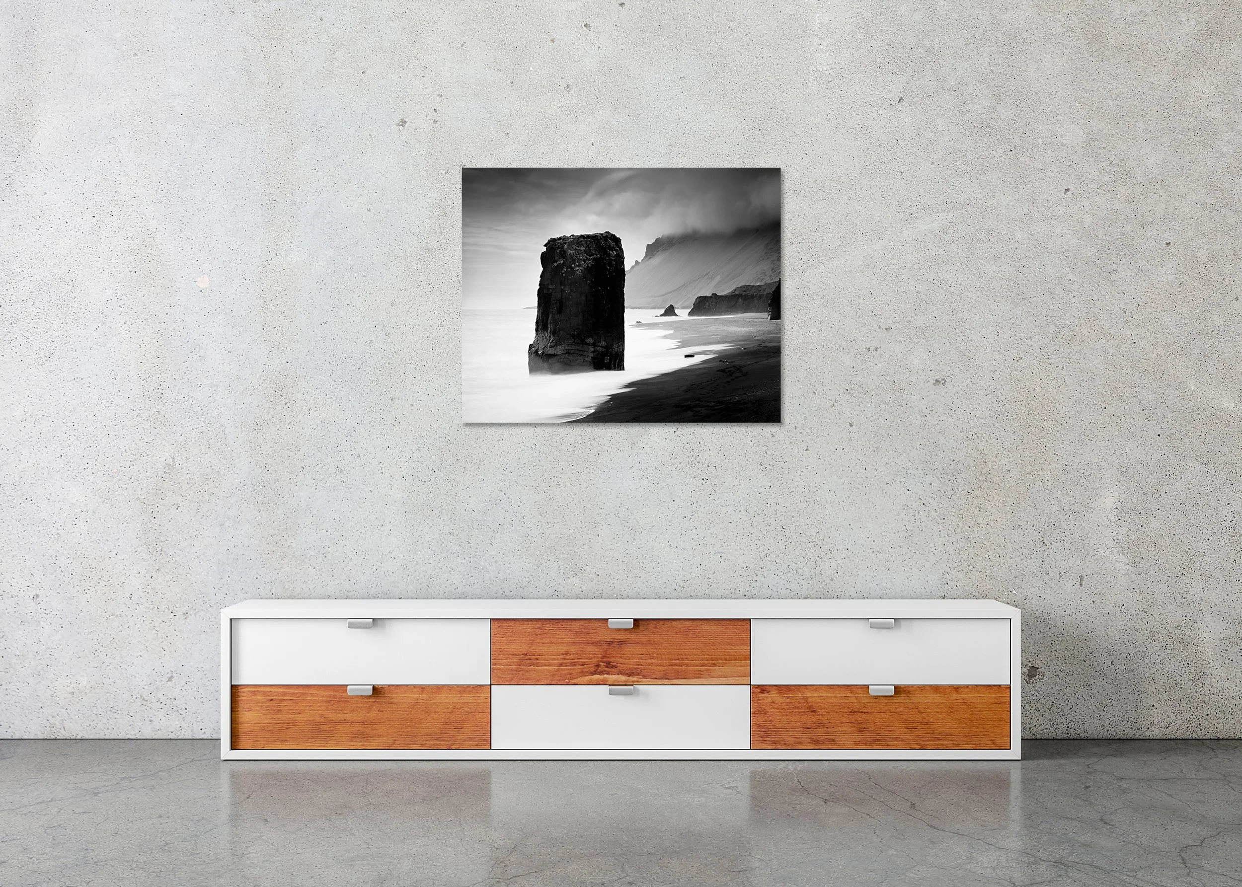 Flooded Rock – Black Beach, Iceland, frameless black-and-white photograph on aluminium Dibond displayed in a minimalist interior. Photo by Gerald Berghammer.