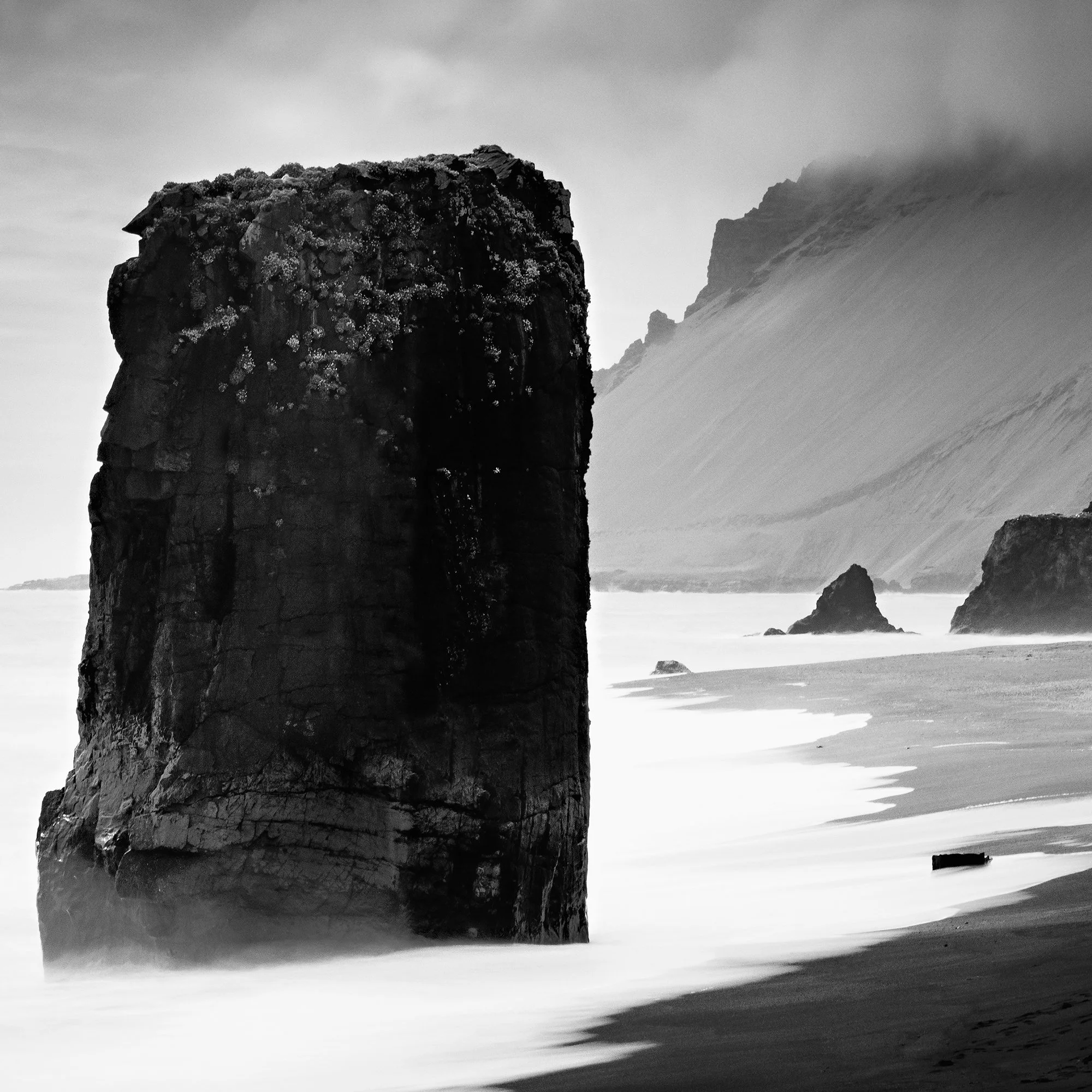 Gerald Berghammer - Black and white Photography. Coastal landscape featuring large sea stacks, sandy shoreline and cliffs with mist over the distant hills. Print detail 3