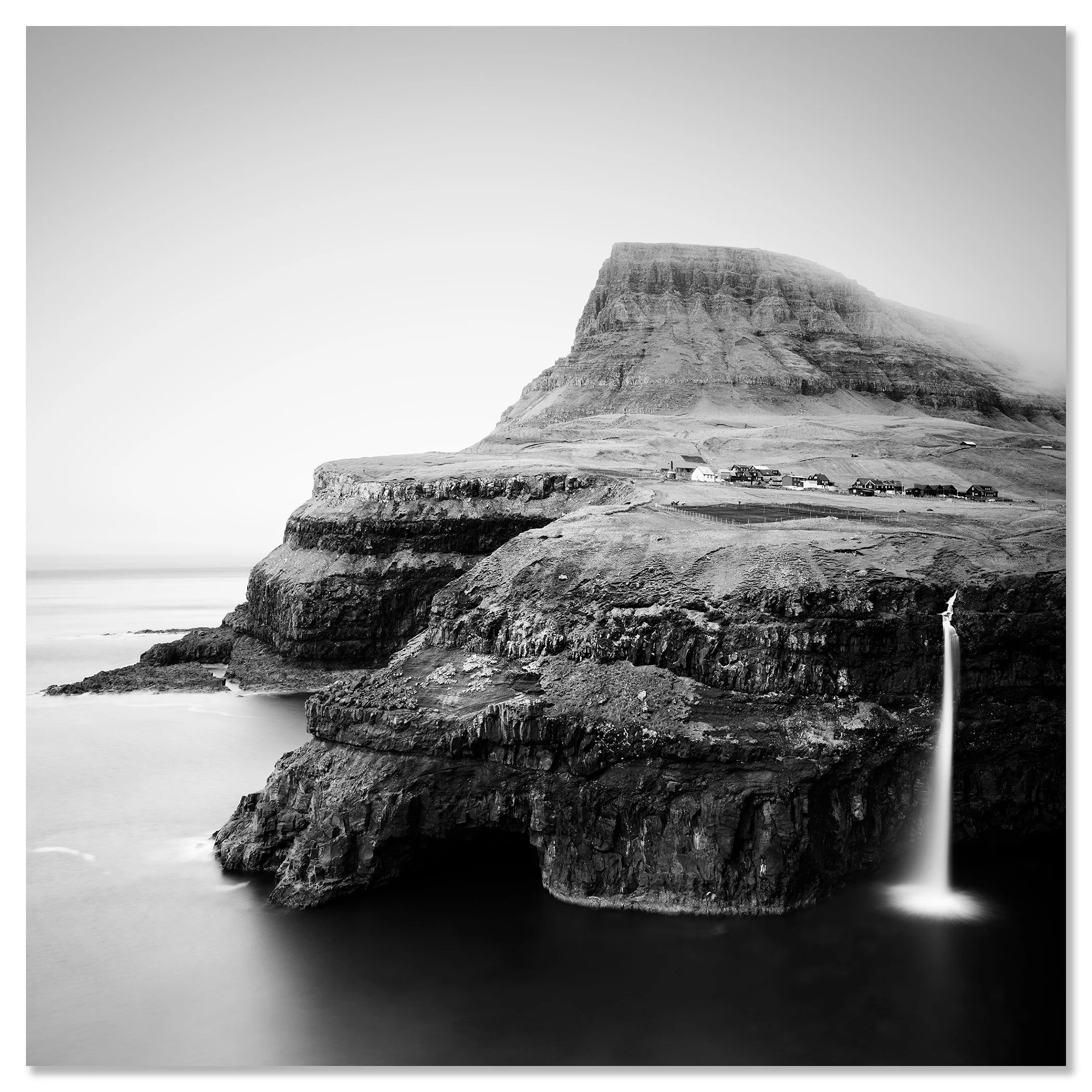 Waterfall cascading down a high sea cliff to a village by the North Atlantic Ocean – dibond frameless