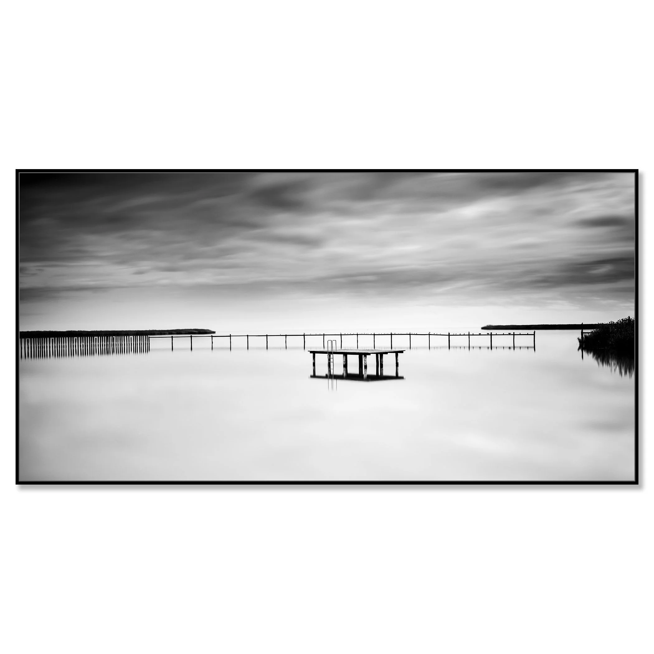 © 2023 Gerald Berghammer - Black and white minimalist waterscape. A calm body of water with a floating dock and a pier in the background, under a cloudy sky. Chromaluxe framed black
